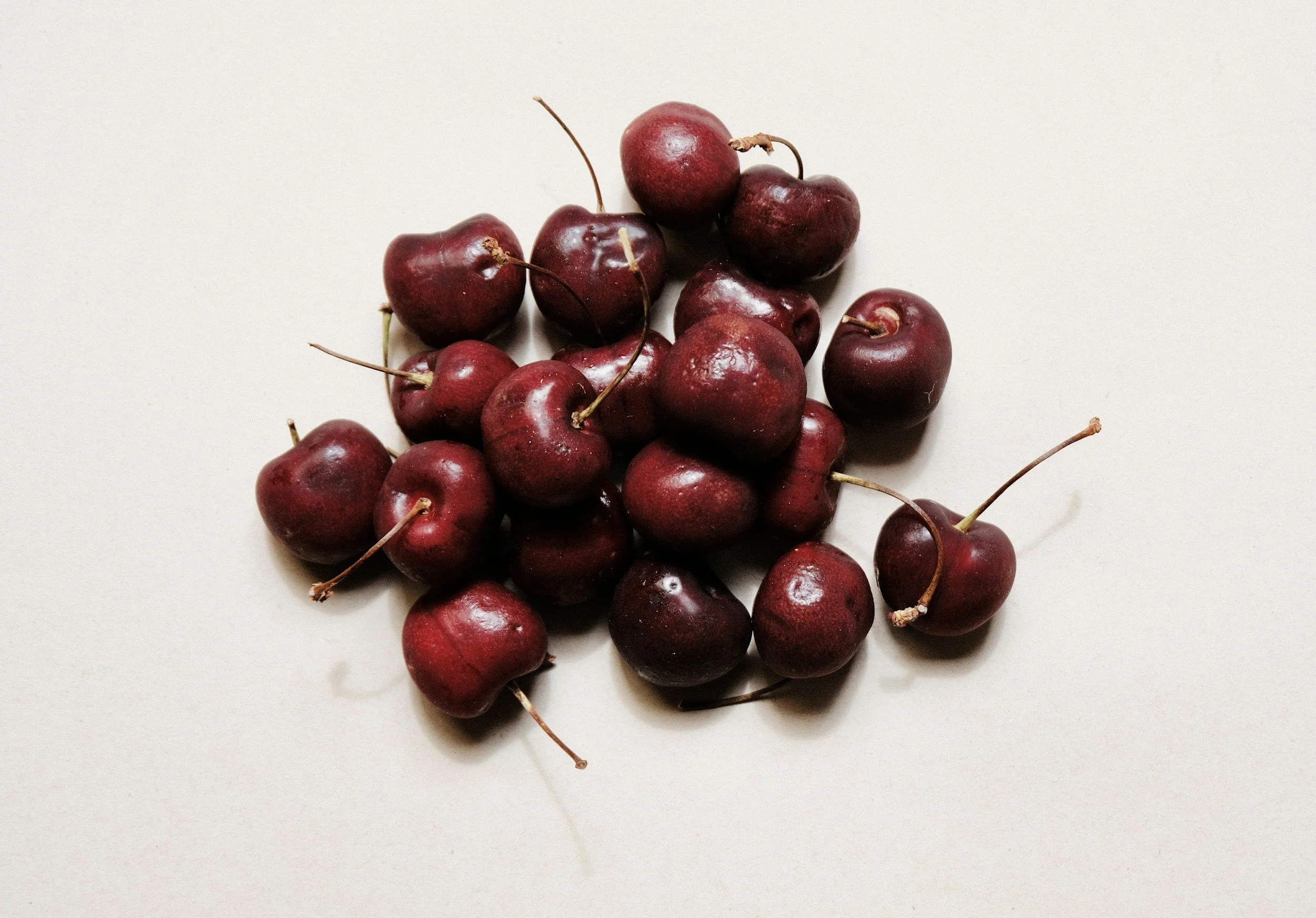 Une poignée de cerises rouges sur un fond blanc.