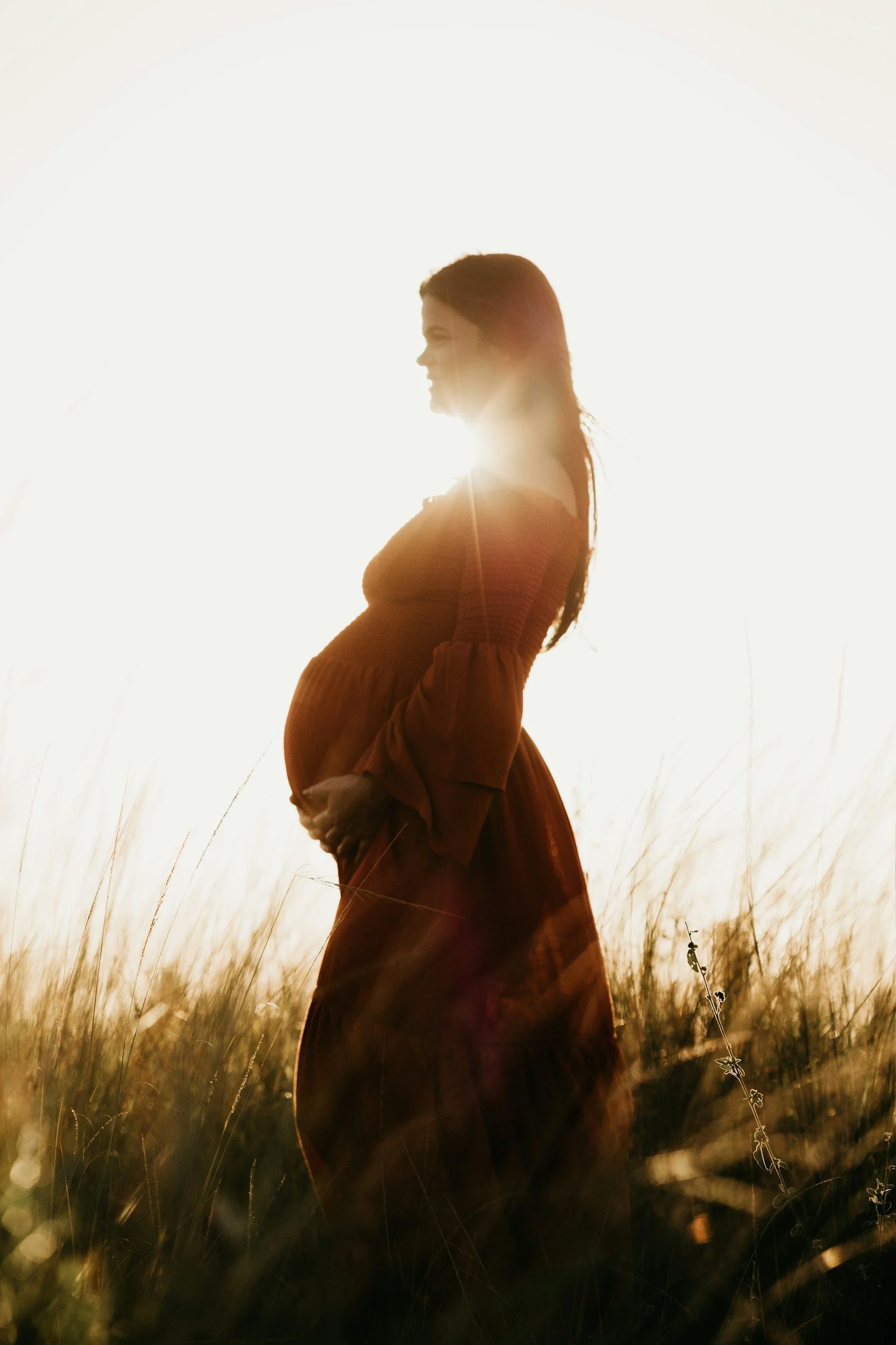 Femme enceinte portant une robe longue dans un champ ensoleillé