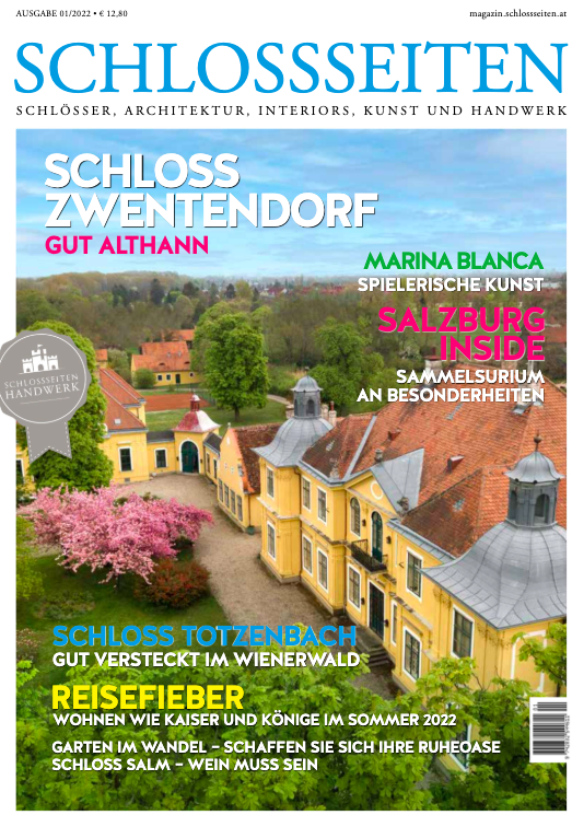 Couverture du magazine SCHLÖSSEN avec une vue panoramique d'un château coloré entouré de jardins, arbres en floraison et bâtiments historiques, avec des titres en plusieurs couleurs sur fond de ciel ensoleillé.