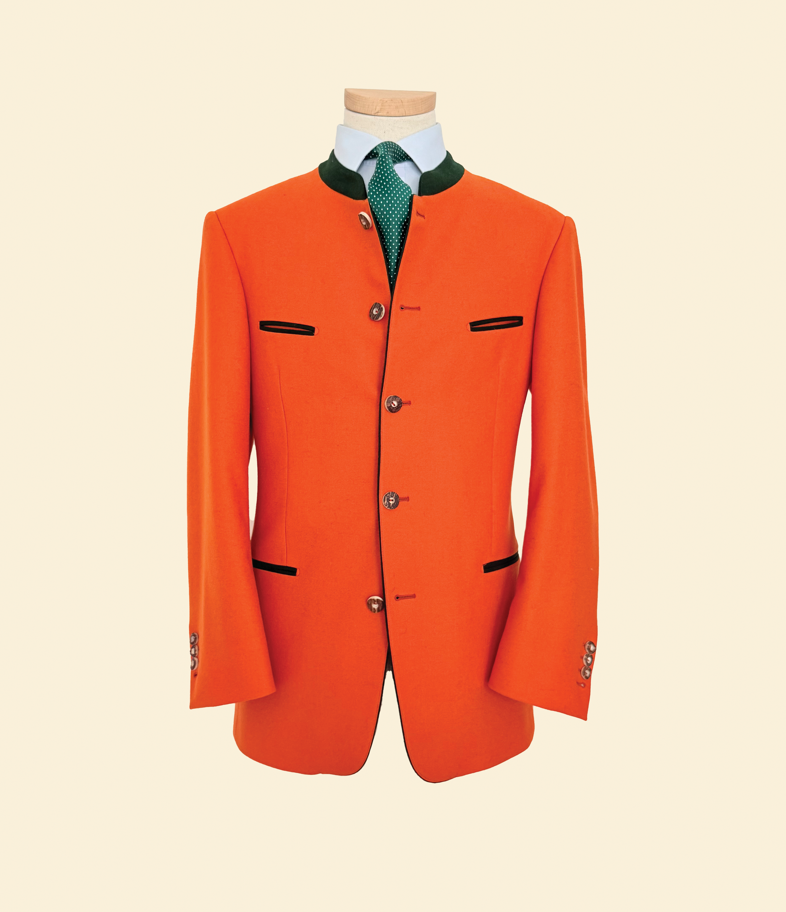 Costume traditionnel allemand, veste orange avec col vert, chemise blanche, cravate verte à pois blancs.