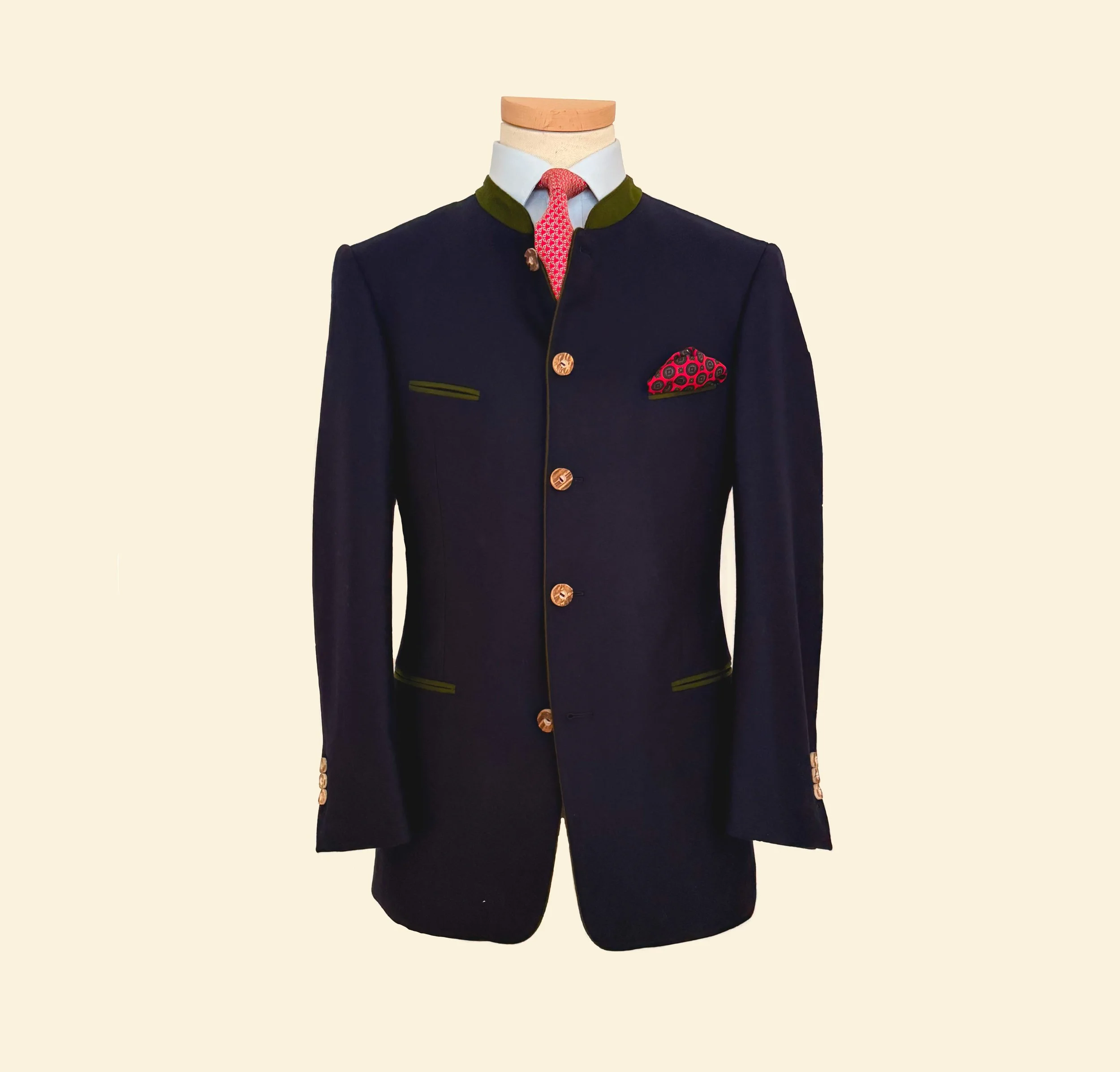 Costume traditionnel, veste noire avec boutons en or, col vert foncé, poche à mouchoir rouge avec motifs, chemise blanche, cravate rouge à motifs