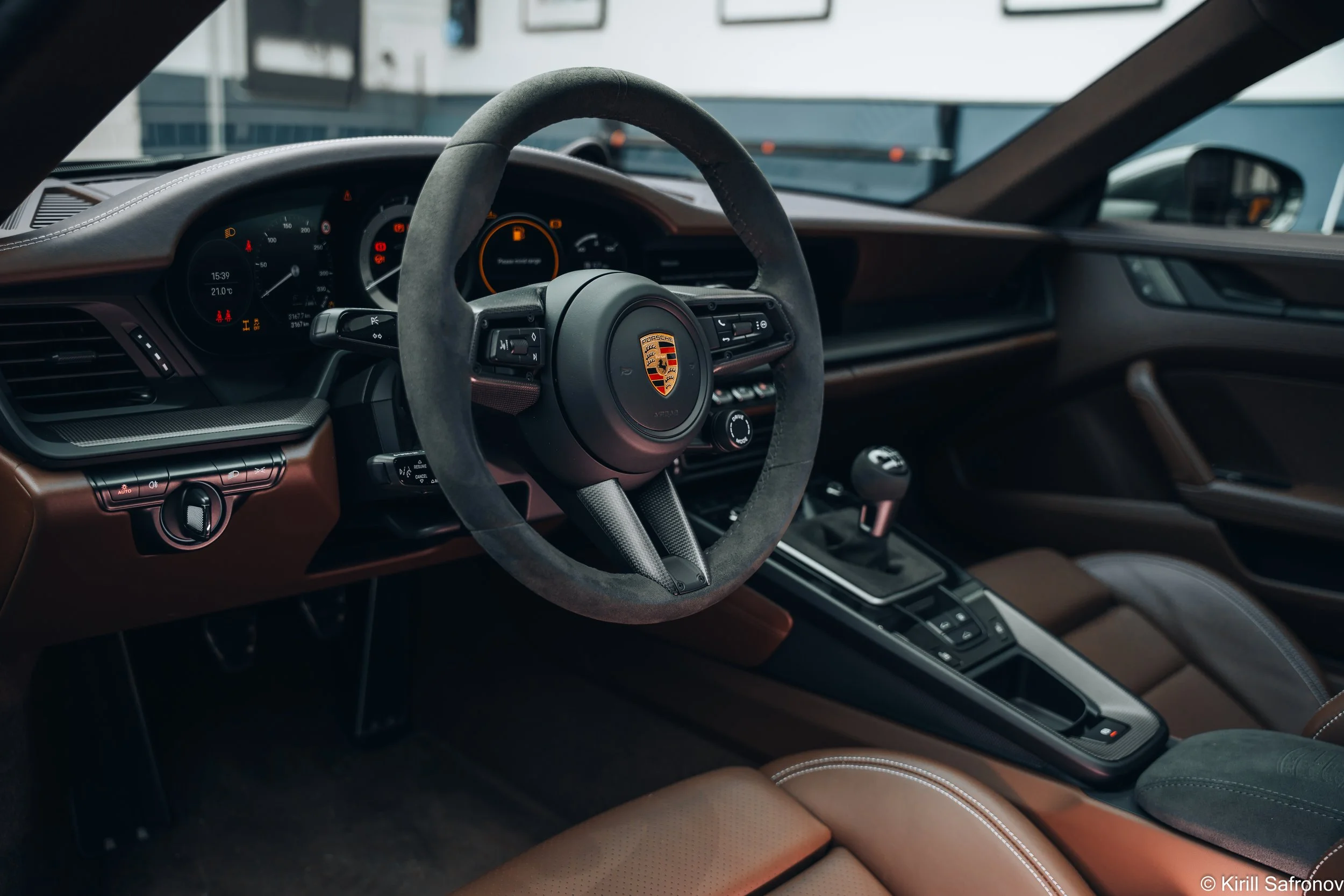Brown Porsche 911 Carrera GTS interior photo showing the luxury dashboard, sport steering wheel, and driver controls.