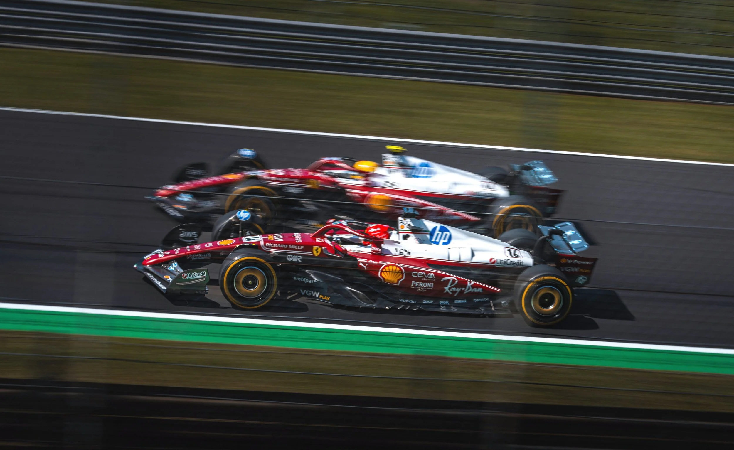 Photo of two Ferrari Formula 1 cars competing on the Monza circuit during the Italian Grand Prix, with motion blur emphasizing speed, racing intensity, and motorsport action. Lewis Hamilton and Charles Leclerc