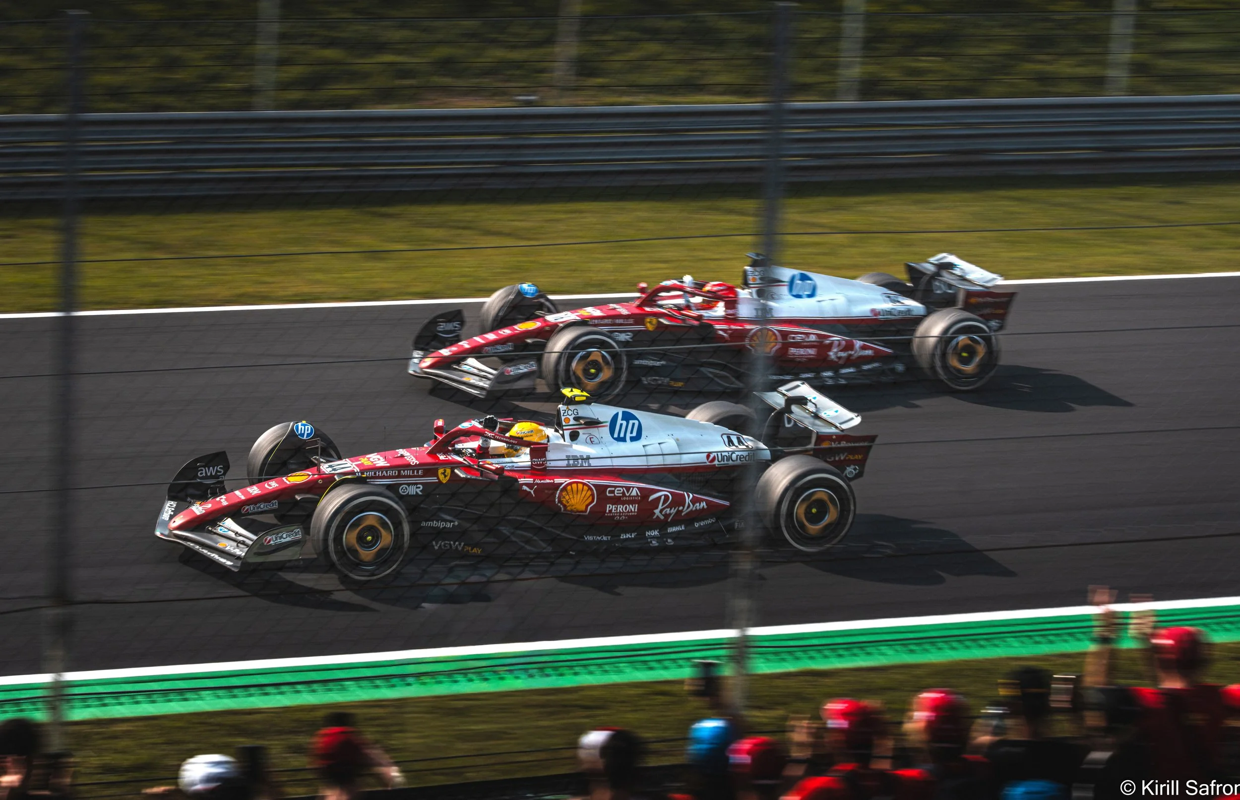 Photo of two Ferrari Formula 1 cars competing on the Monza circuit during the Italian Grand Prix, with motion blur emphasizing speed, racing intensity, and motorsport action. Lewis Hamilton and Charles Leclerc