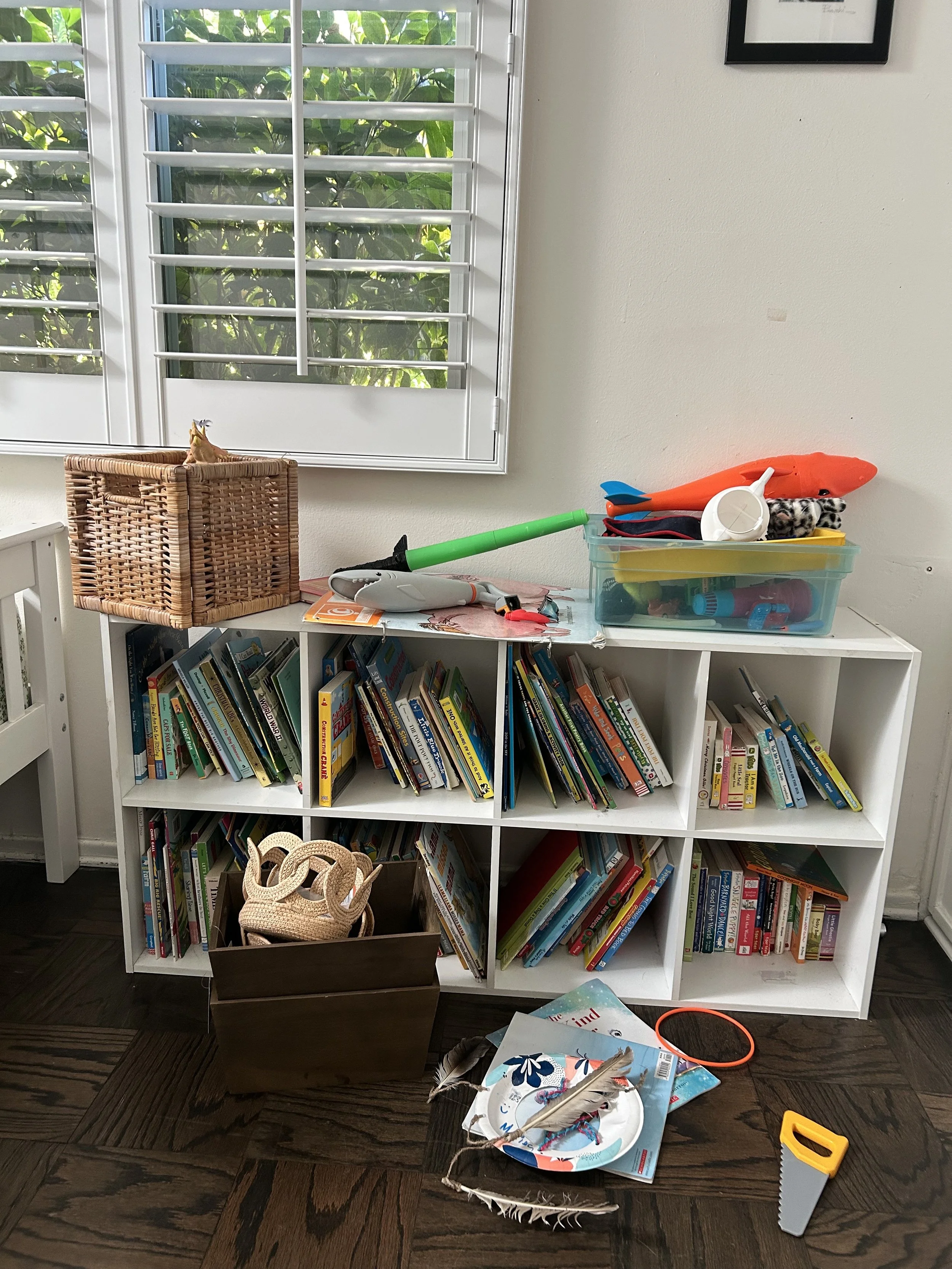 Disorganized children's bookshelf with books, toys, and art supplies scattered around.