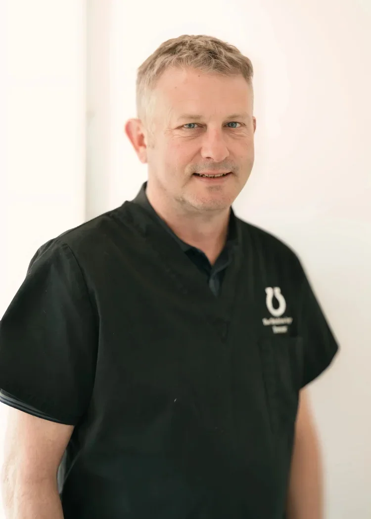 A man dressed in a black nurse or medical uniform standing against a white background.