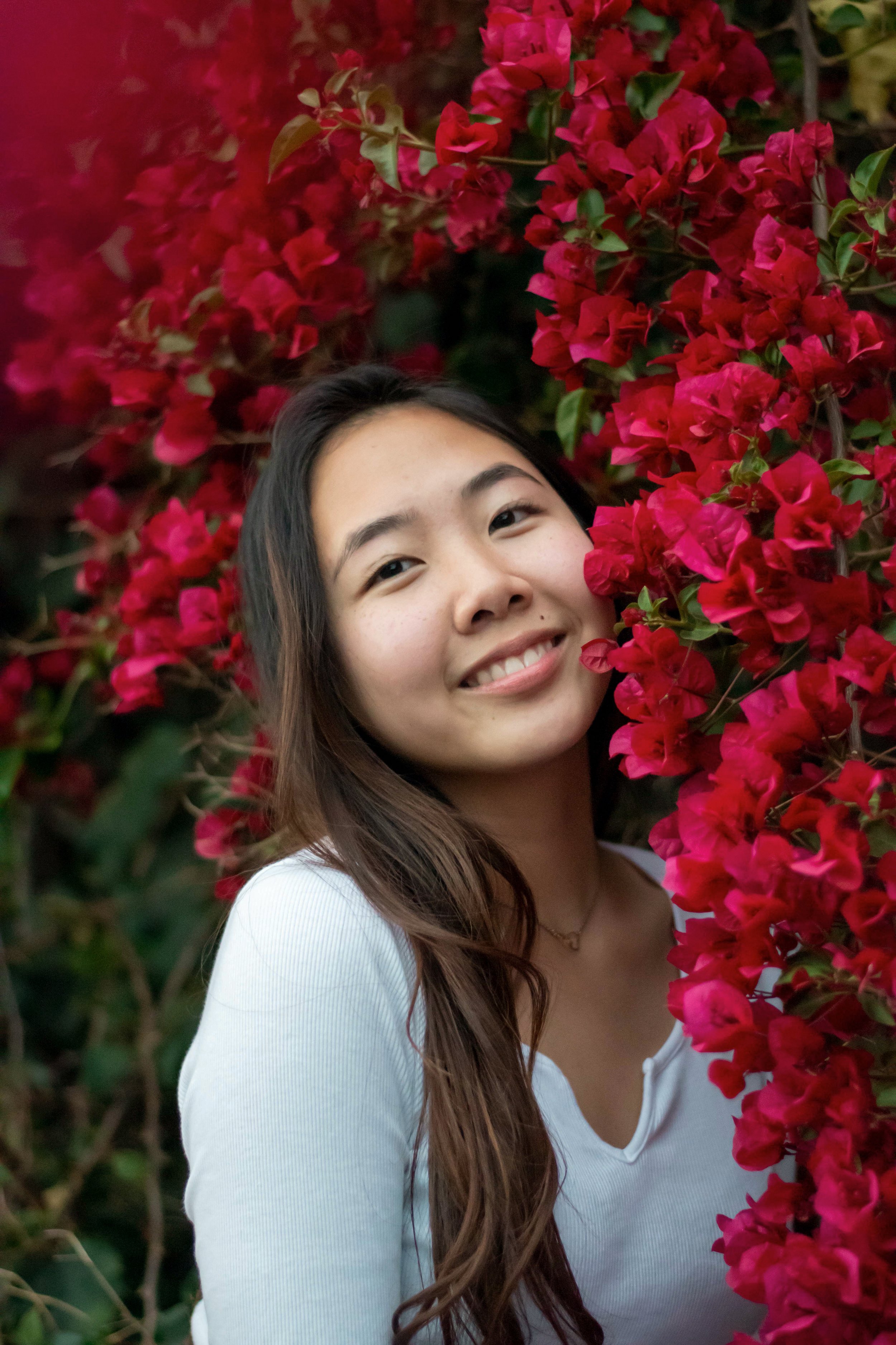 Woman smiling near red flowers