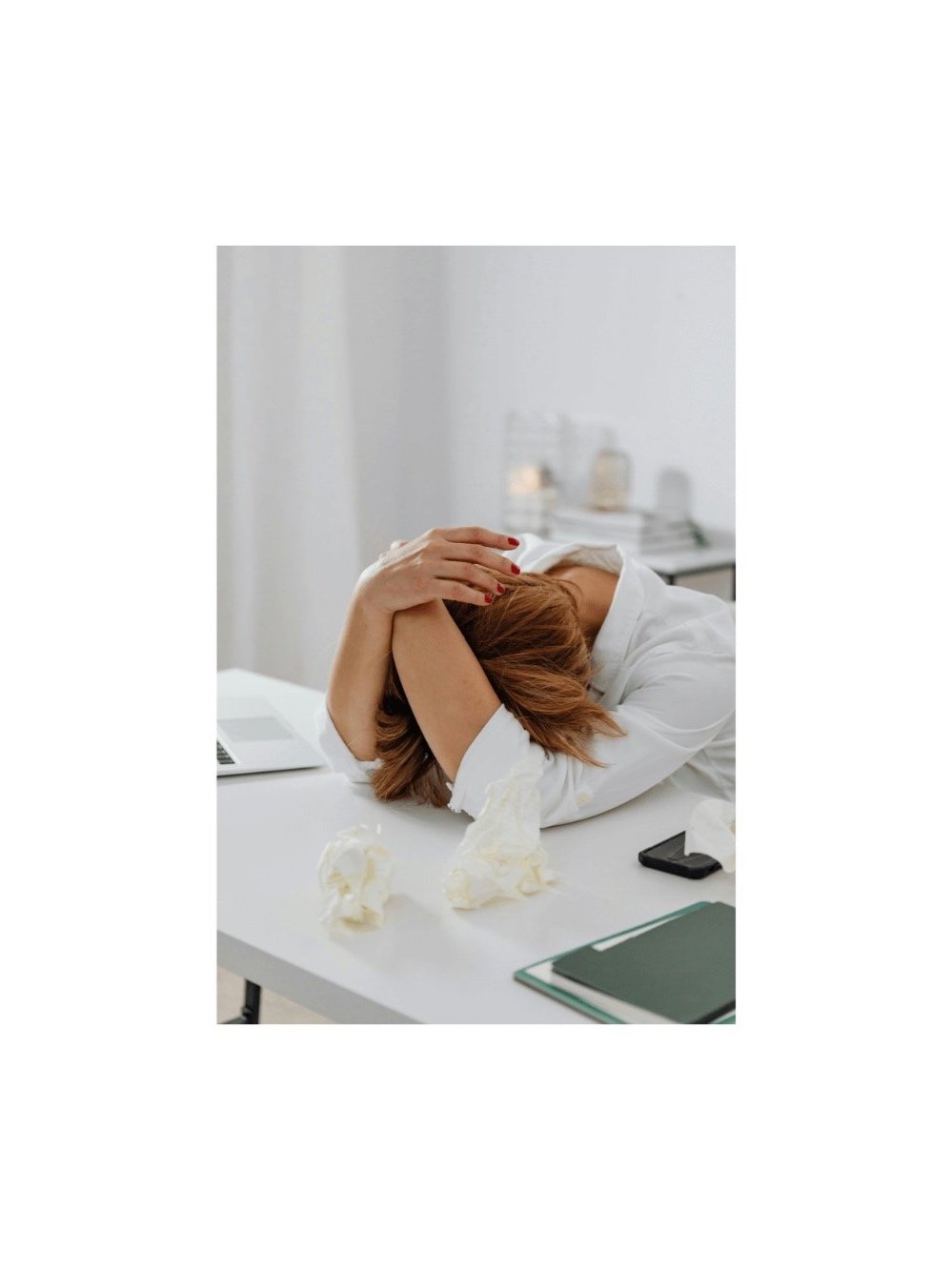 Woman sitting at her desk with her head in her hands, feeling overwhelmed.