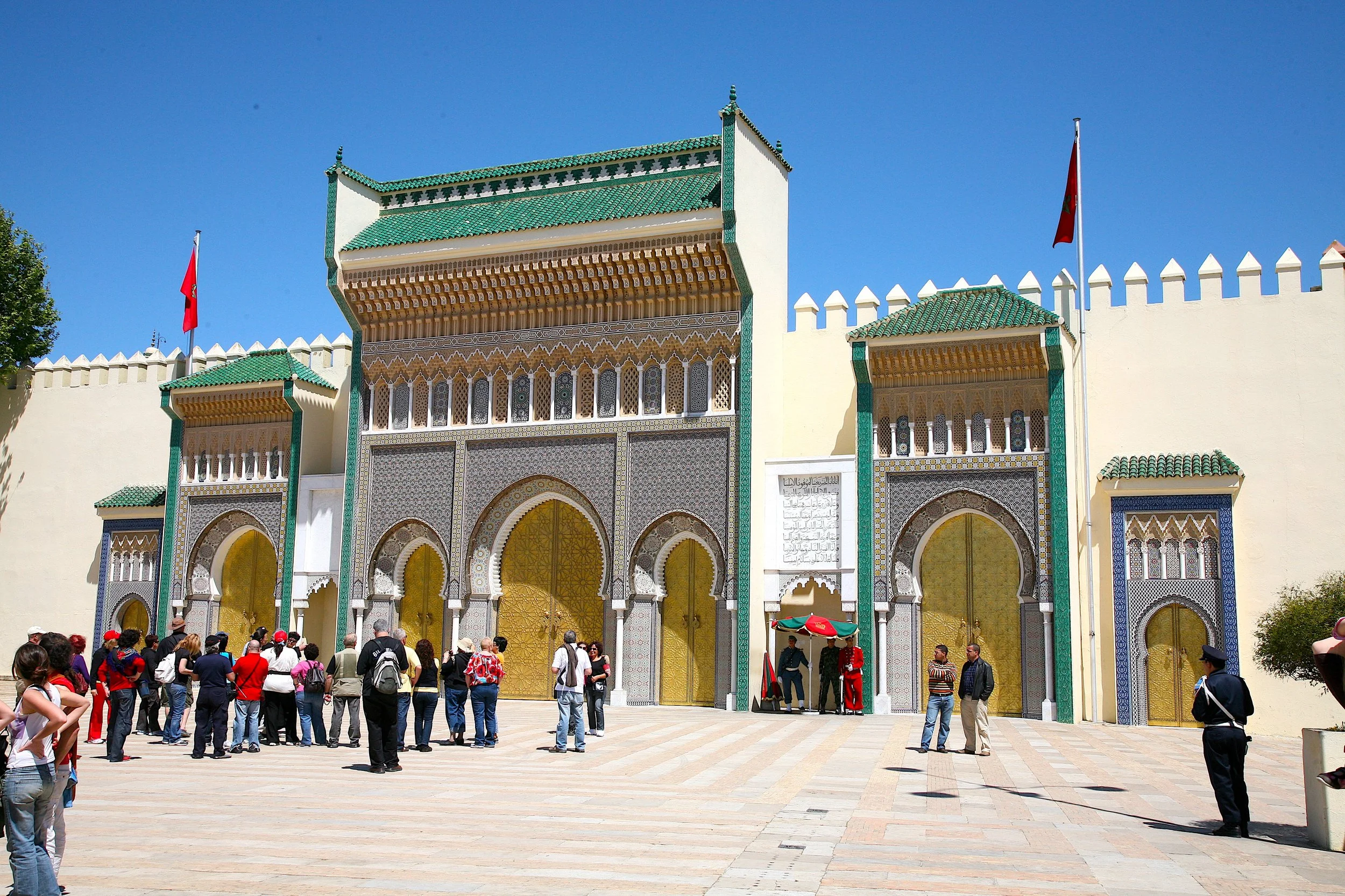 Ornate Royal Palace gates in Fez with colorful tilework and visitors in the square