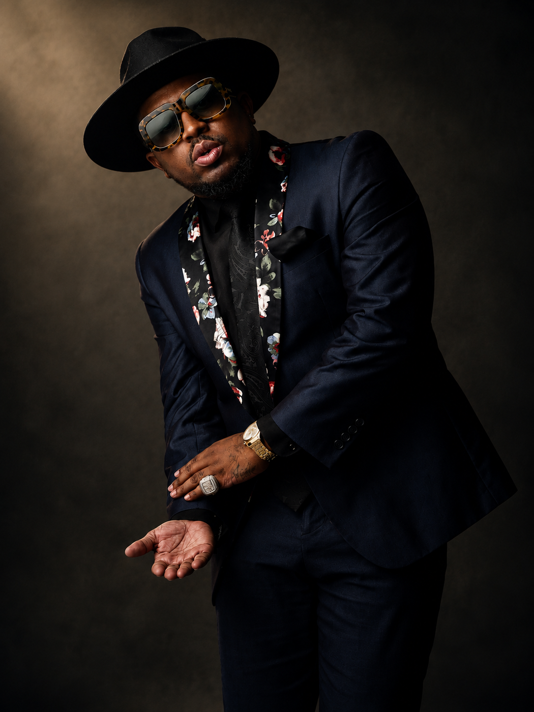 Concert promotional poster for Clay James, featuring a photo of Clay James wearing a wide-brimmed hat, leopard-print sunglasses, jewelry, and a dark suit with a floral scarf. The poster includes event information such as booking contact, social media handle, and available dates for 2026.