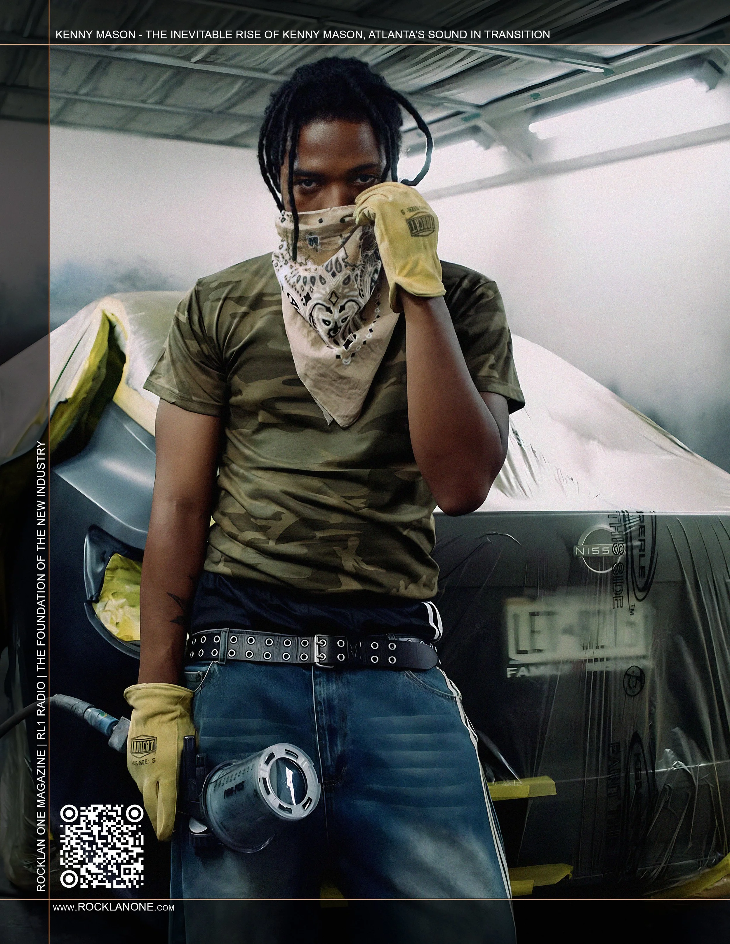 A young man with dreadlocks wearing a bandana face covering, camouflage t-shirt, yellow work gloves, and jeans, holding a welding helmet, standing in front of a car wrapped in plastic inside a workshop or garage.
