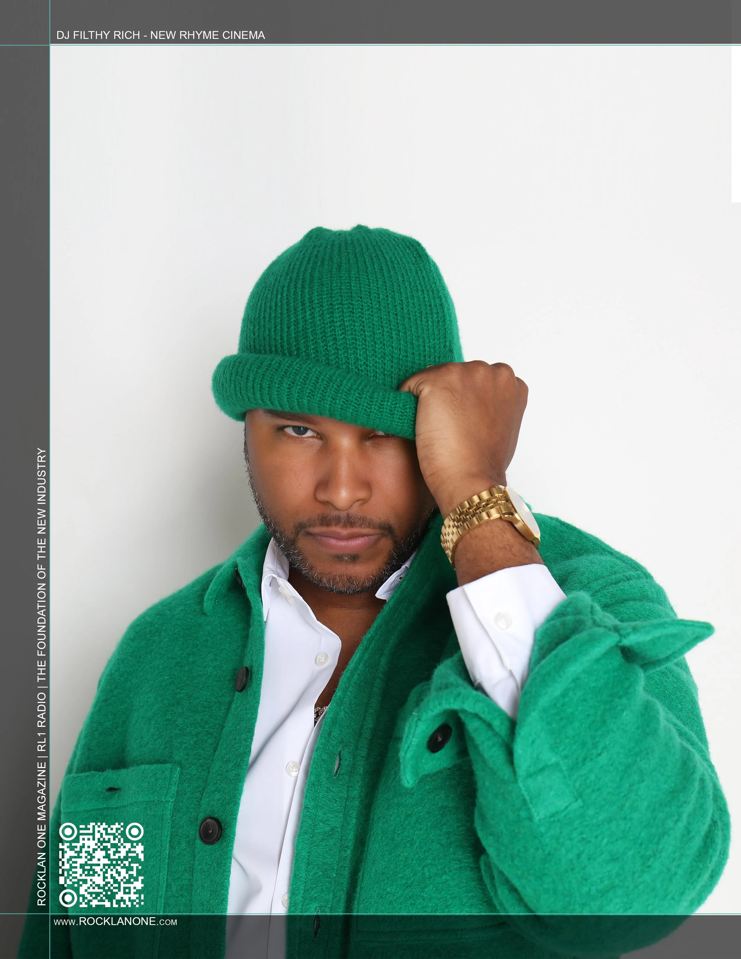A man wearing a green hat and green jacket, adjusting his hat with his right hand, against a plain white background.