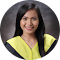 A woman with long dark hair wearing a black blazer over a yellow top, smiling at the camera.