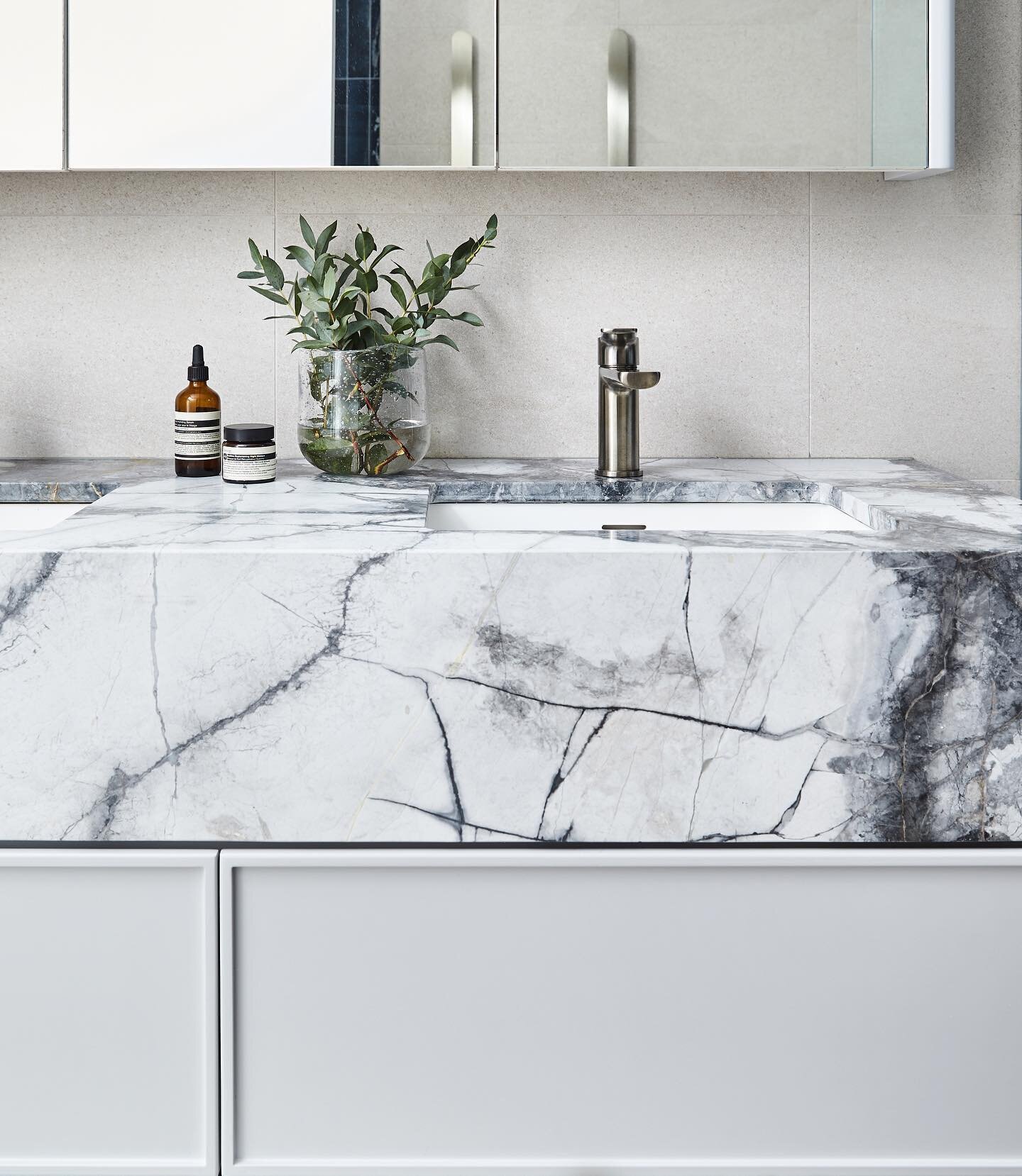 Bathroom details at the Rockley Residence in Rushcutters Bay featuring natural stone on the vanity, complemented by satin nickel tapware and a palette of soft grey tones and deep blue tiles.
Interior Design: @michaelallsoppdesign 
Builder: @acumencor