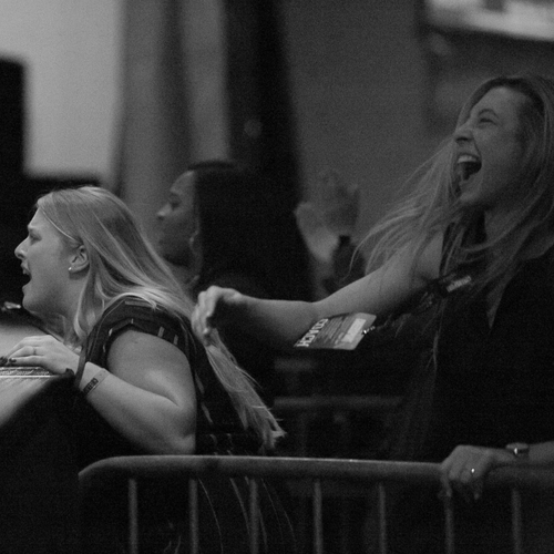 Three women laughing and enjoying themselves at an indoor event or concert.