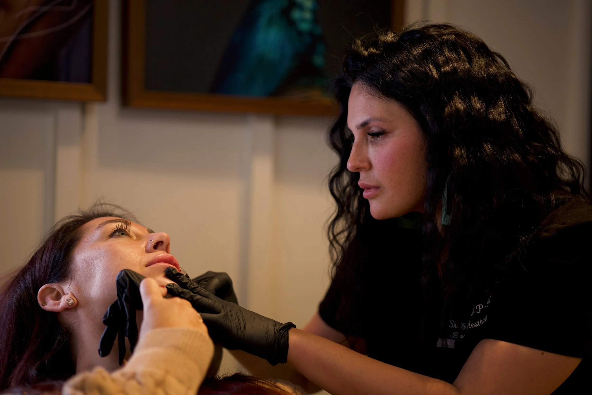 A licensed medical aesthetics provider performing a dermal lip filler treatment  while consulting with a client in a treatment room at Bombshell Aesthetics & Wellness. in Bedford NH.