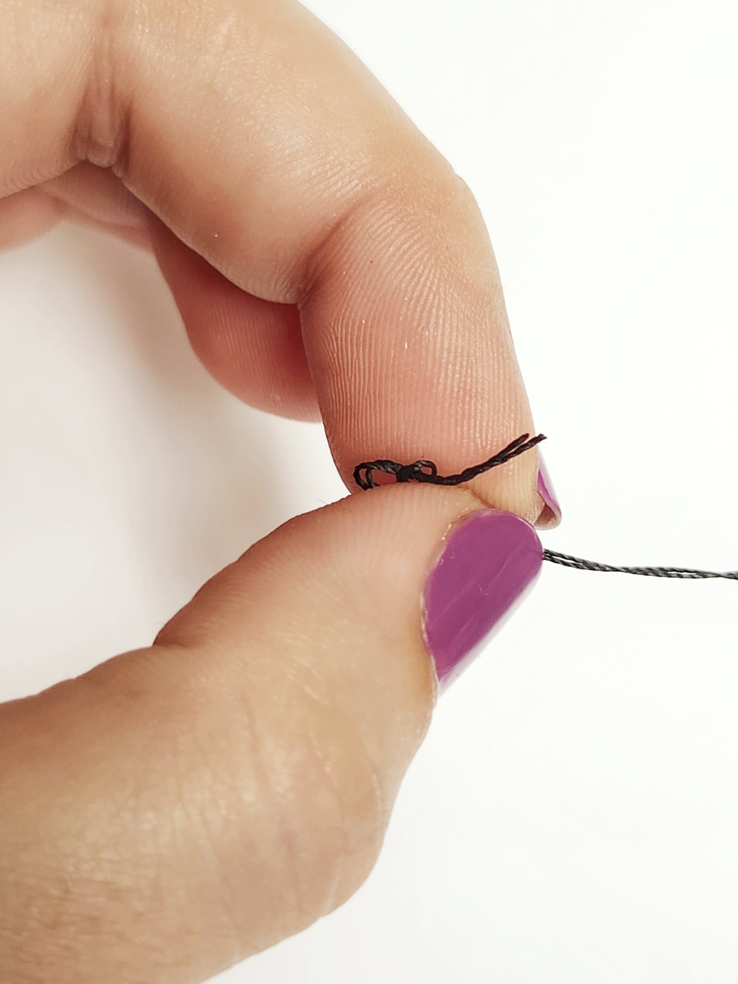 pull down the length of the thread to create a knot