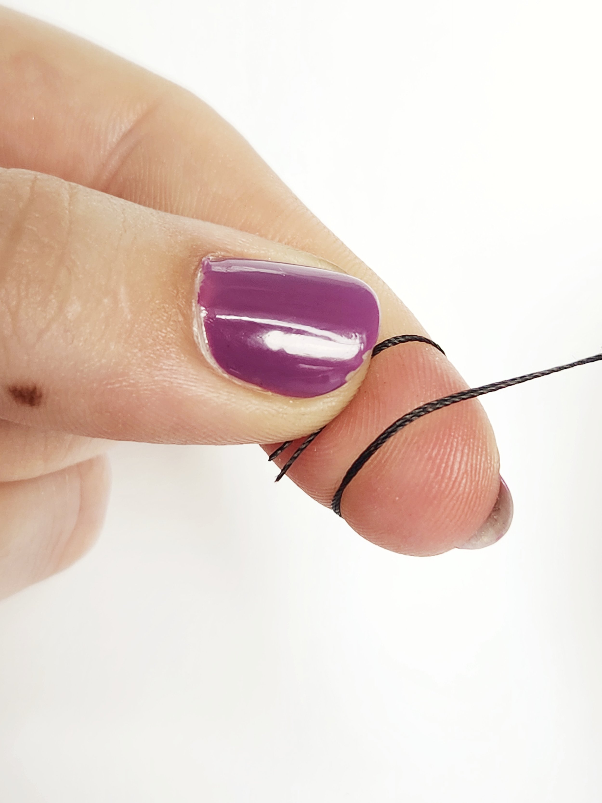 To make a knot, wrap your index finger with the tail end of the thread