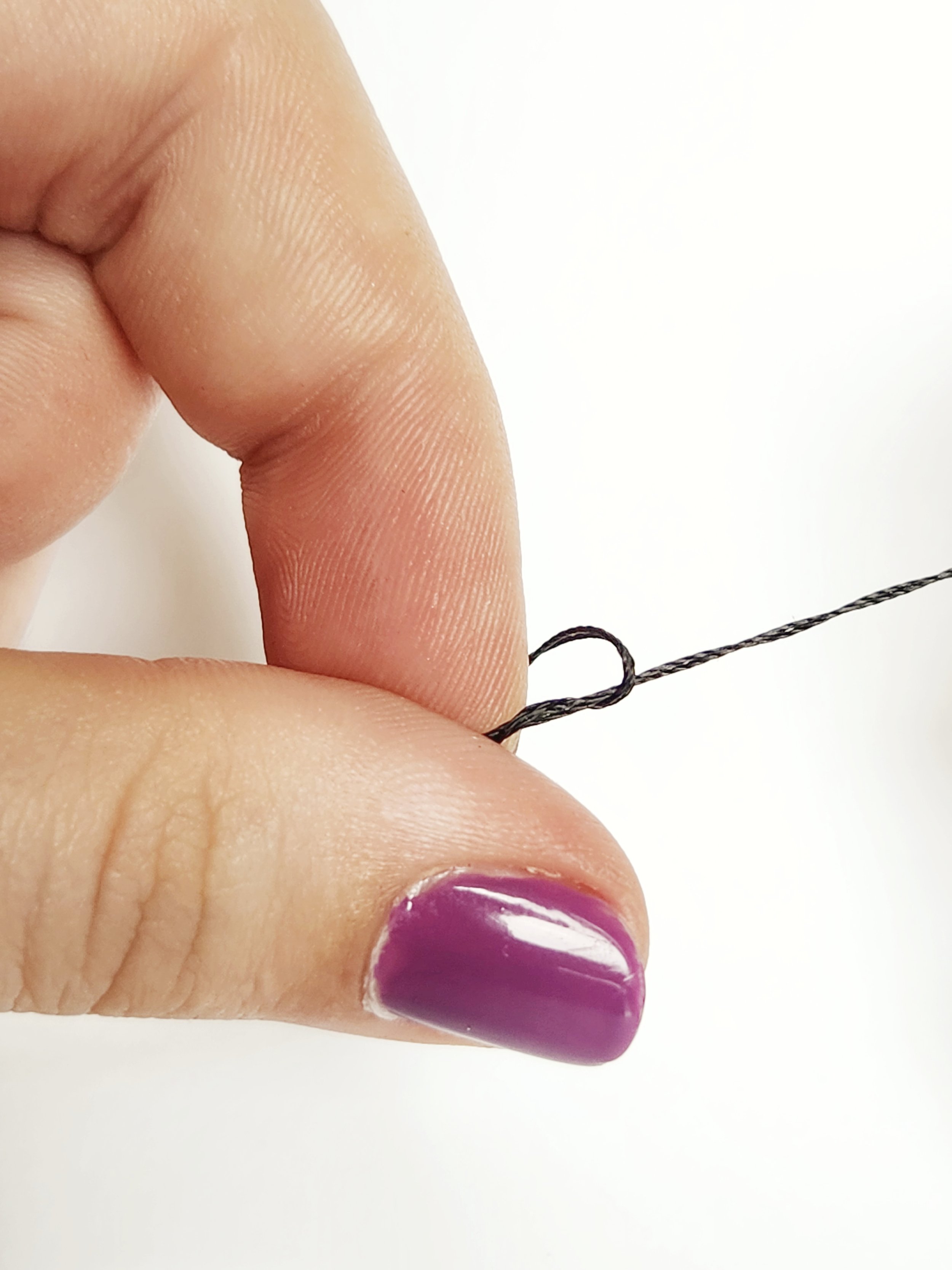 "roll" your thumb towards the tip of your index finger, twisting the thread