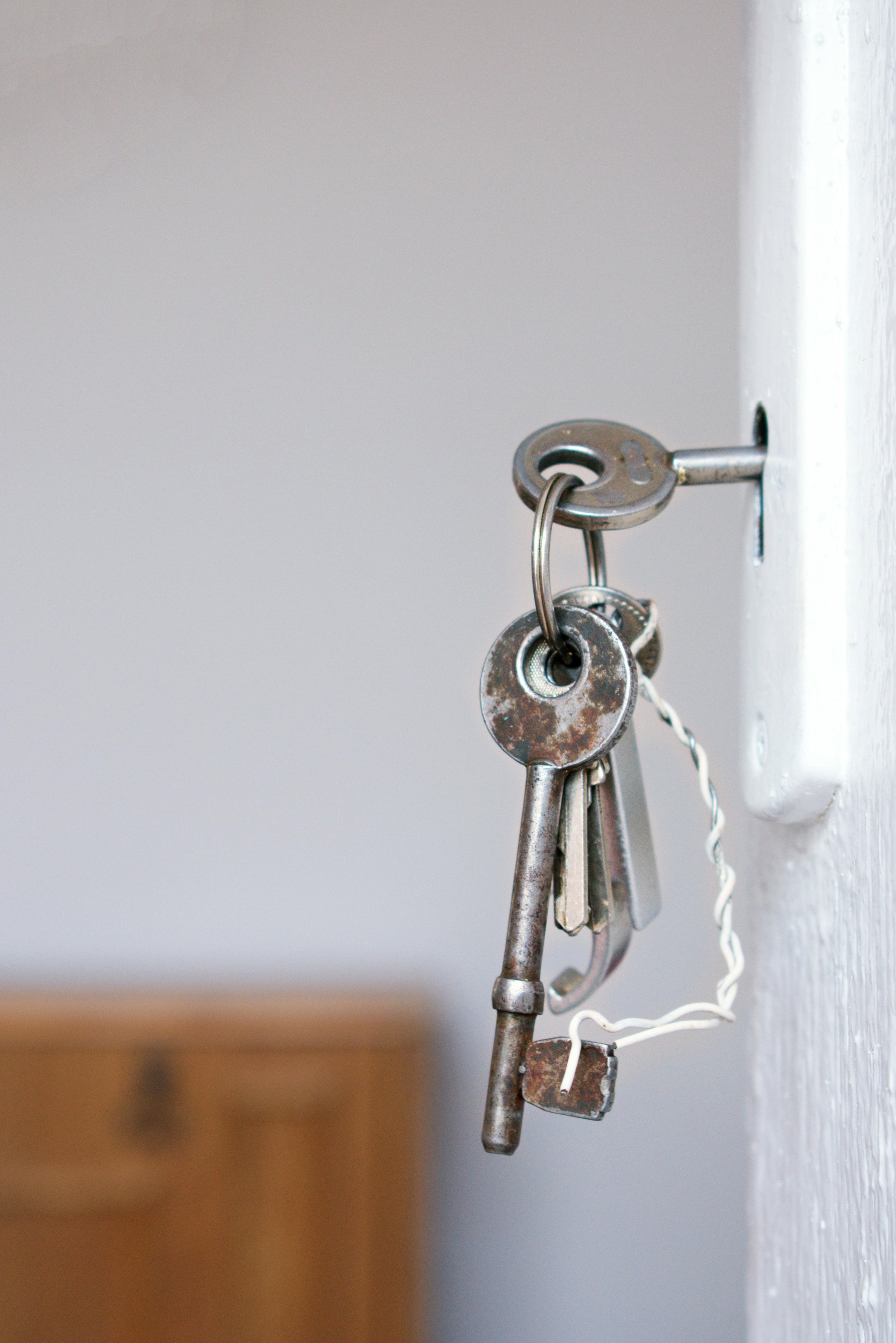 Close-up of a metal keychain holding multiple keys hanging from a wall hook
