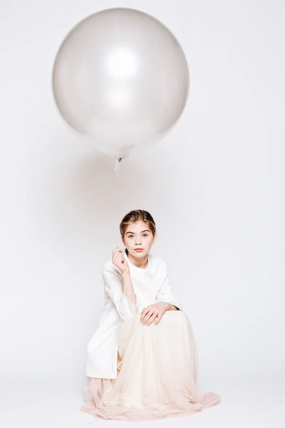 Woman wearing white with a large silver balloon
