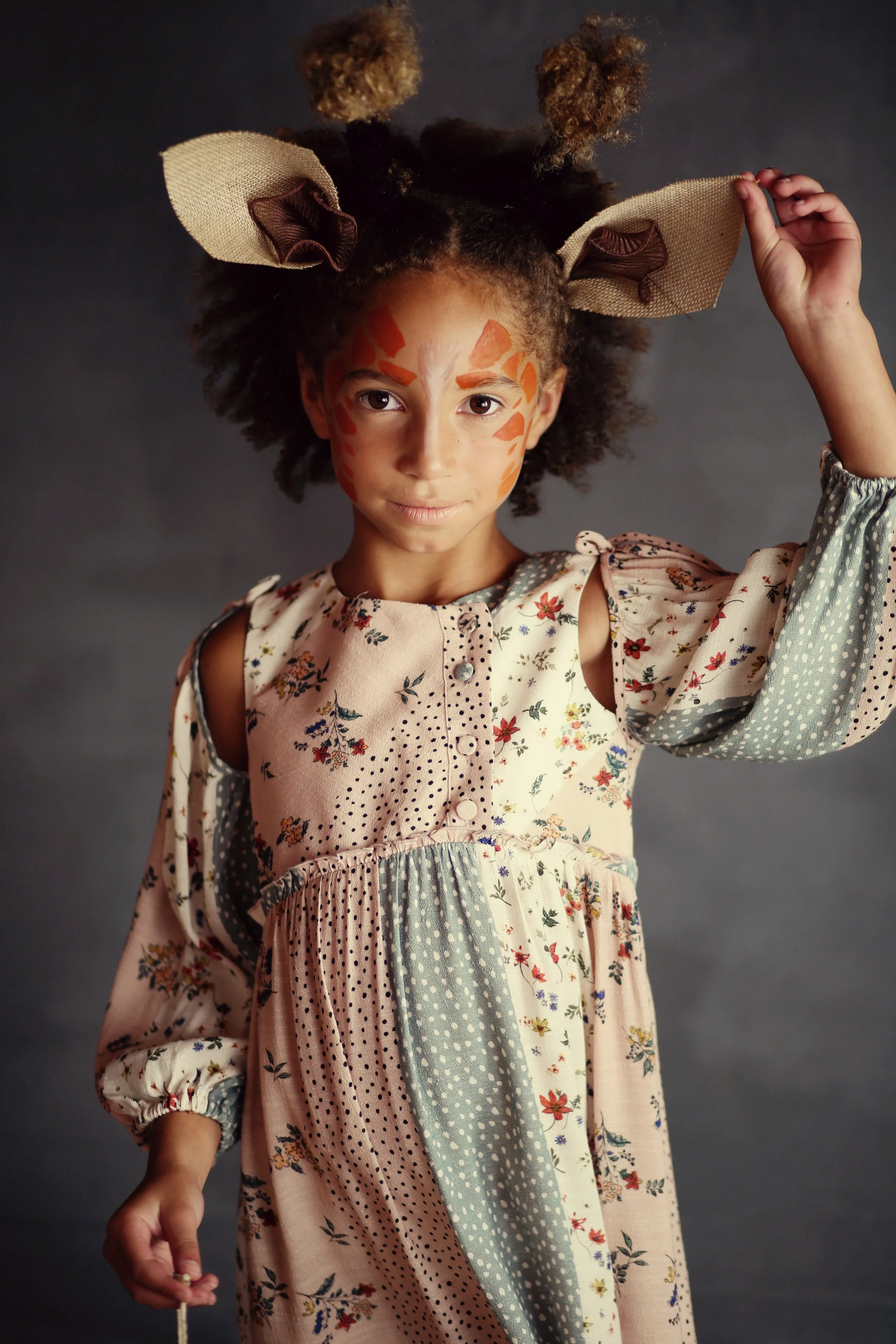 Child in floral dress with giraffe face paint and ears