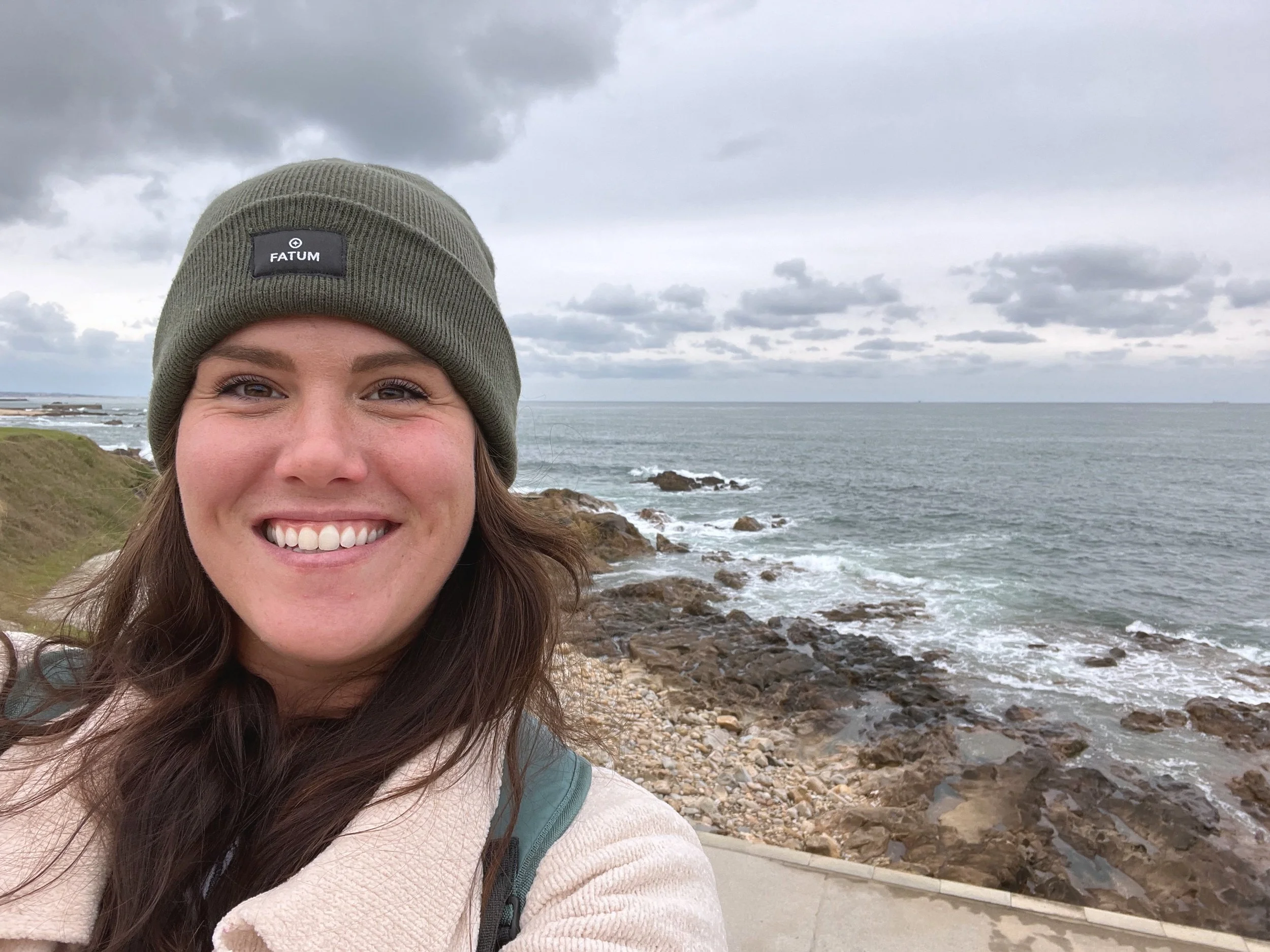 image of Emily smiling on a hike along the ocean
