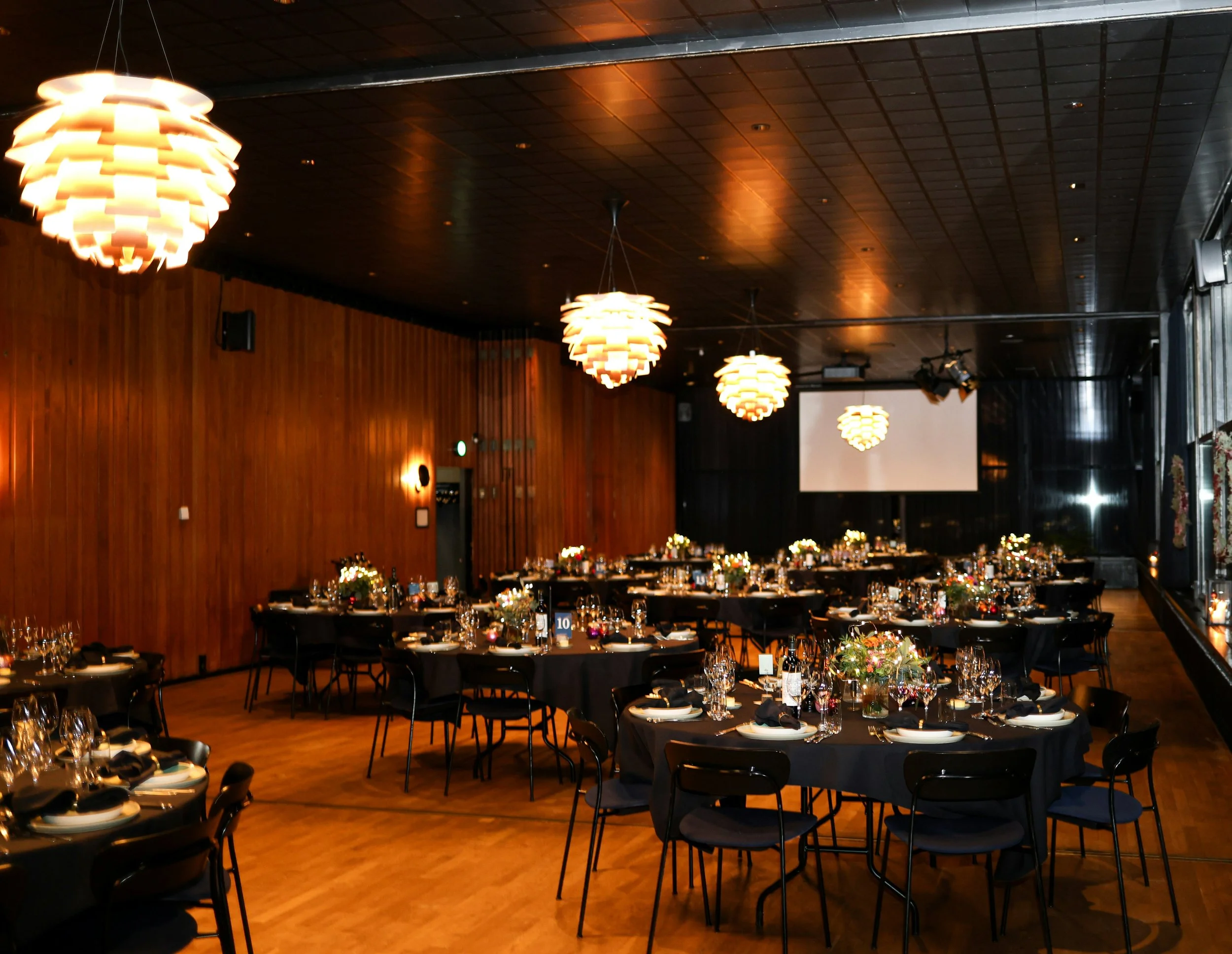 Corporate awards dinner setup with recognition slideshow screen