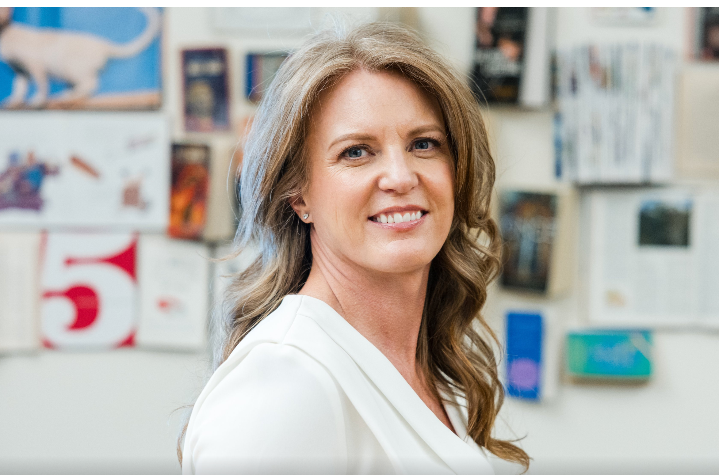 Headshot of a smiling woman with books in the background