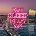 Neon sign on the city waterfront that says Eat Sleep Play AC.