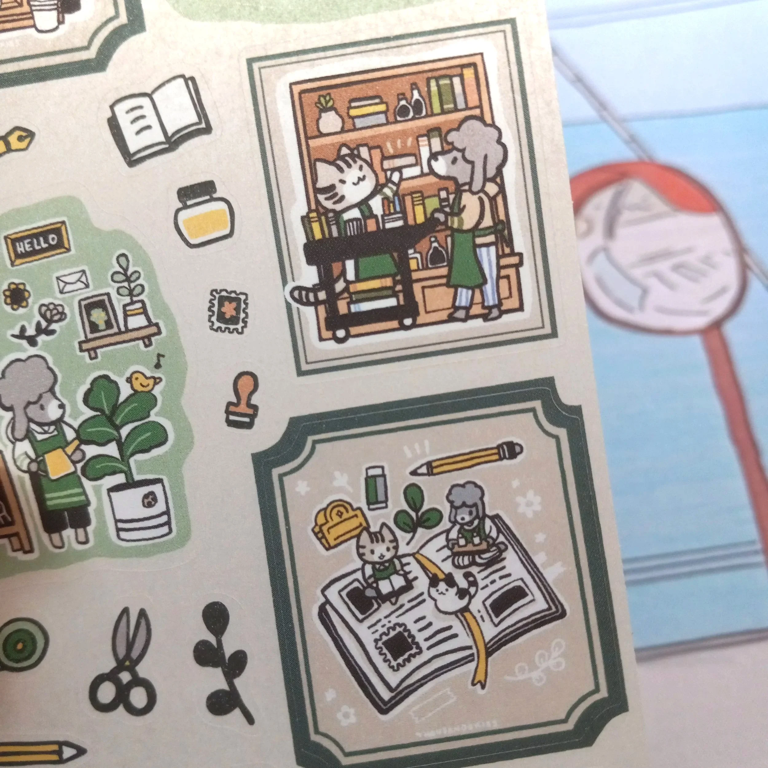 Close-up view of washi sticker sheet “Stationery Store” showing cats and dogs interacting in a stationery shop environment