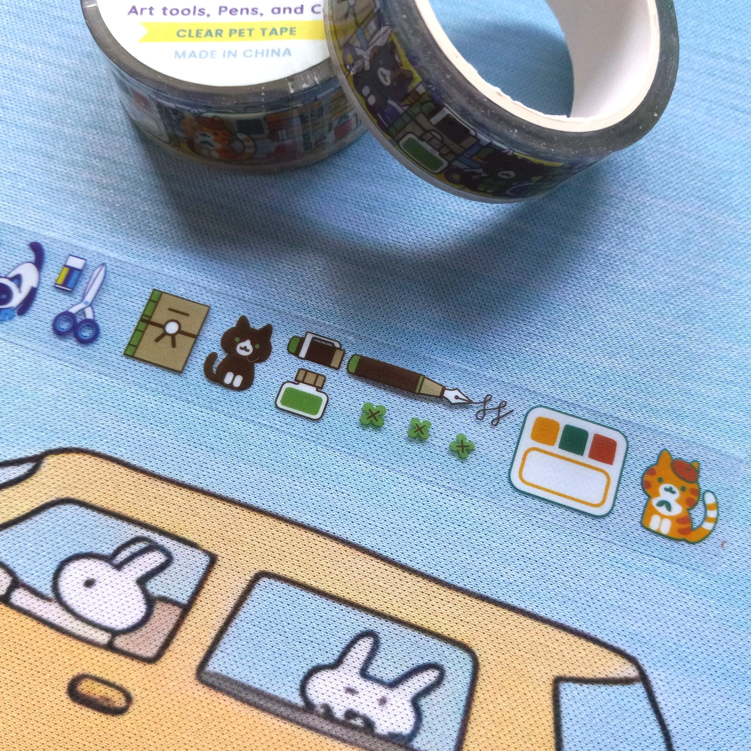Macro view of clear PET decorative tape featuring pens and whimsical cat illustrations by Thousand Skies