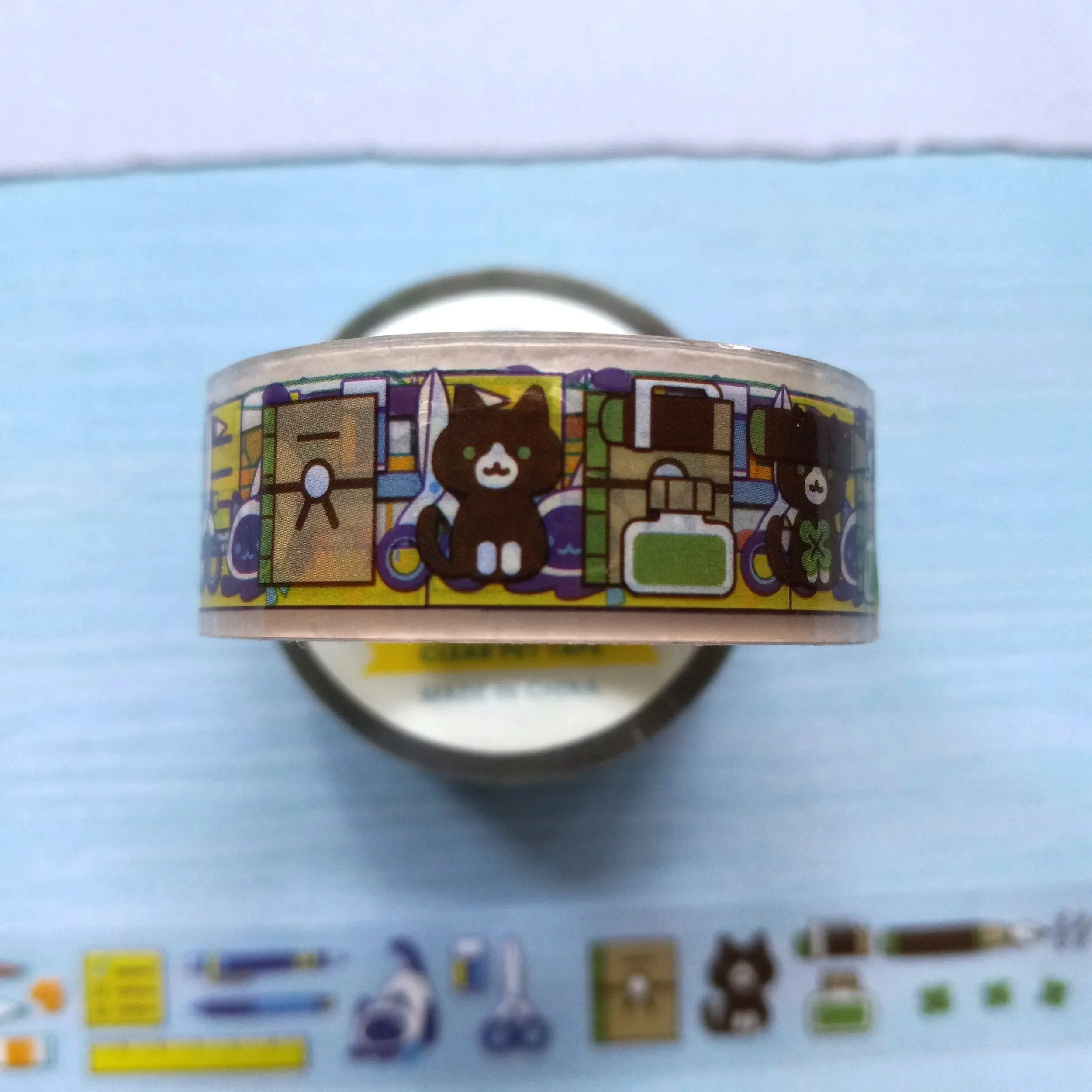 Close-up of clear PET tape showing cats, pens, and art tools illustration on transparent background