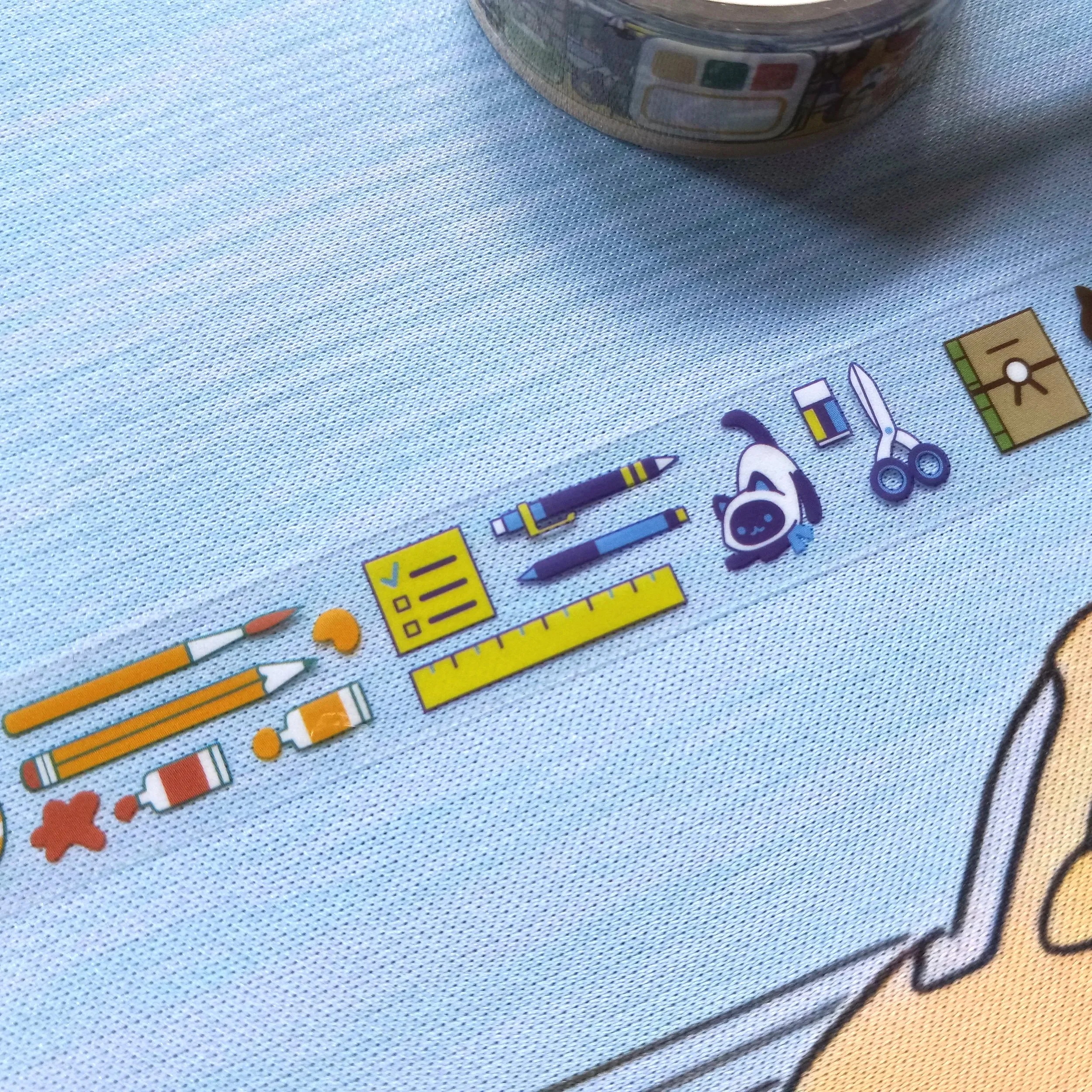 Close-up detail of clear PET tape showing illustrated cats and art tools on transparent background