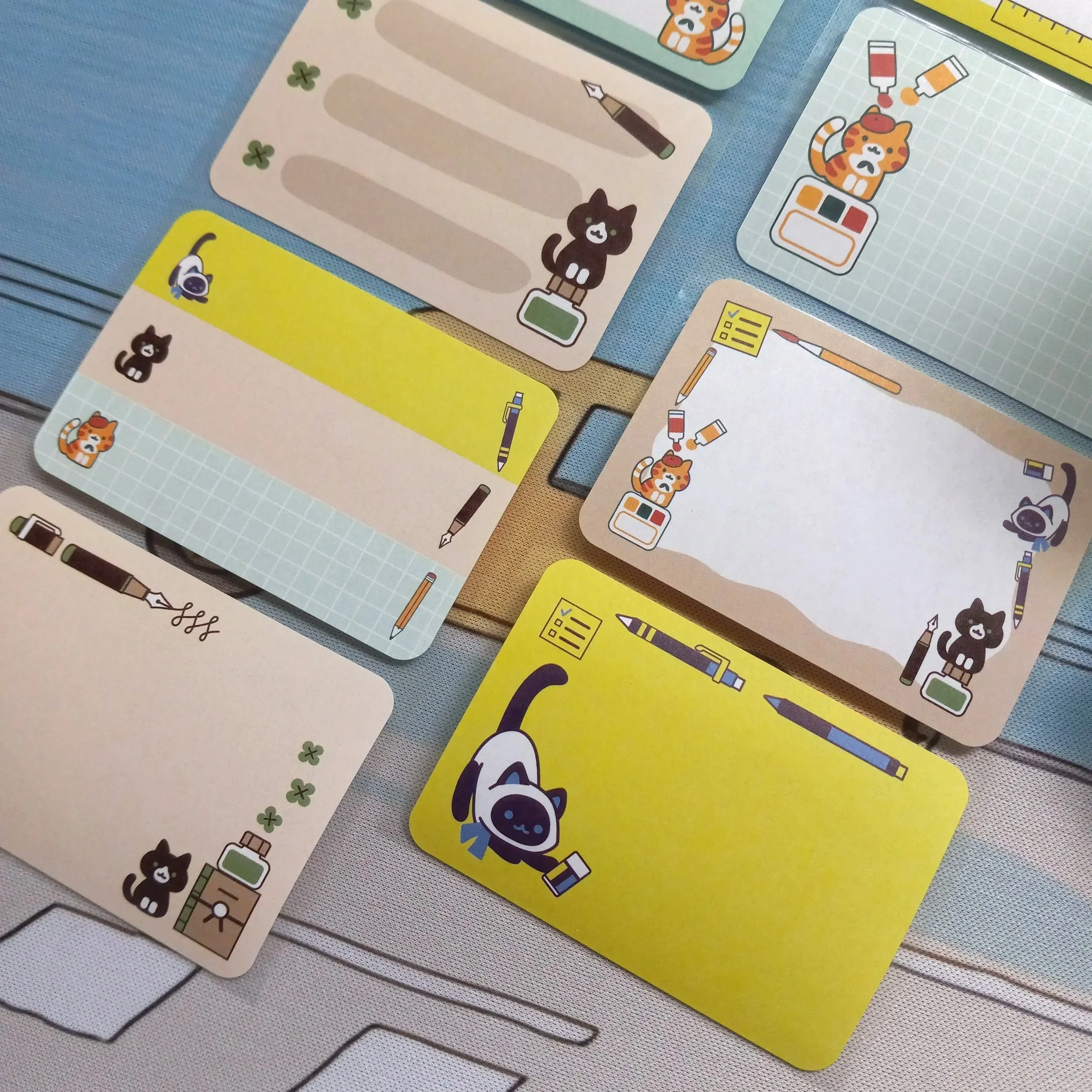 Close-up detail of “Stationery Cats” paper roll labels featuring illustrated cats with pens and paper on each label