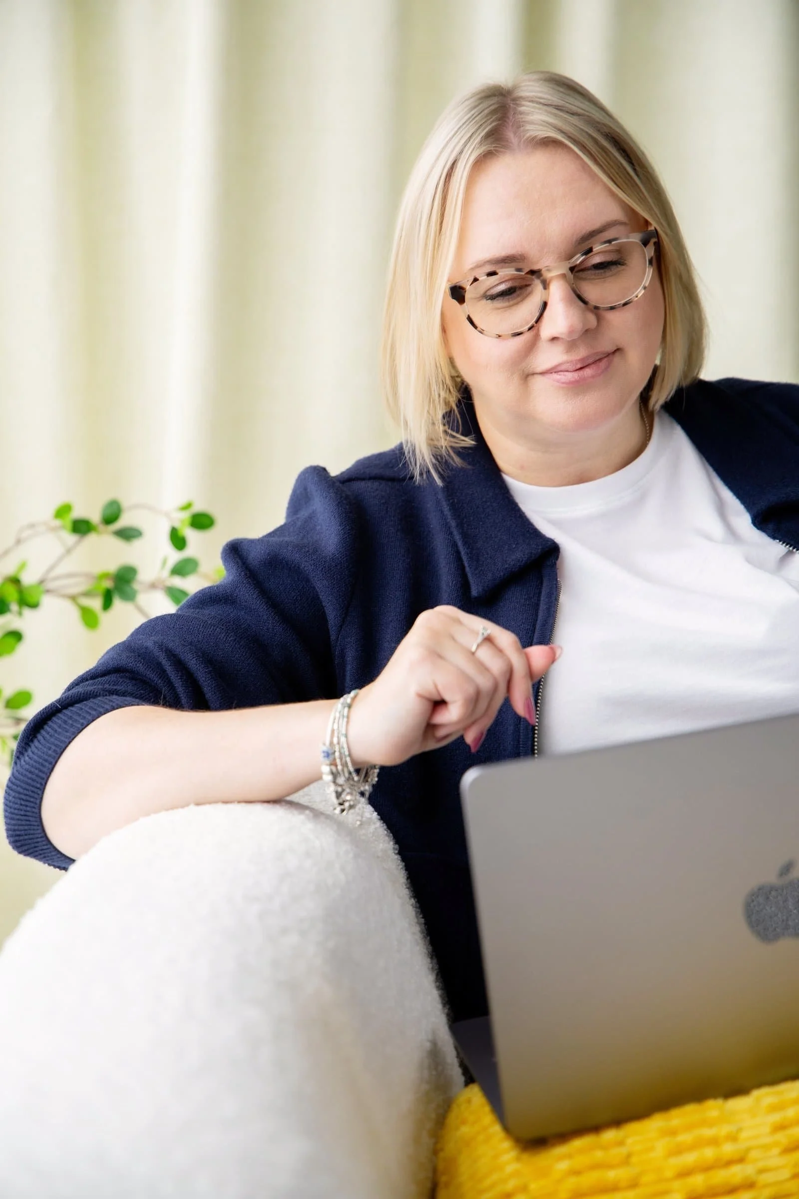 Sadie Finch, virtual assistant, sitting on a sofa with laptop demonstrating her virtual admin support services for small businesses from her home in Ely, Cambridgeshire