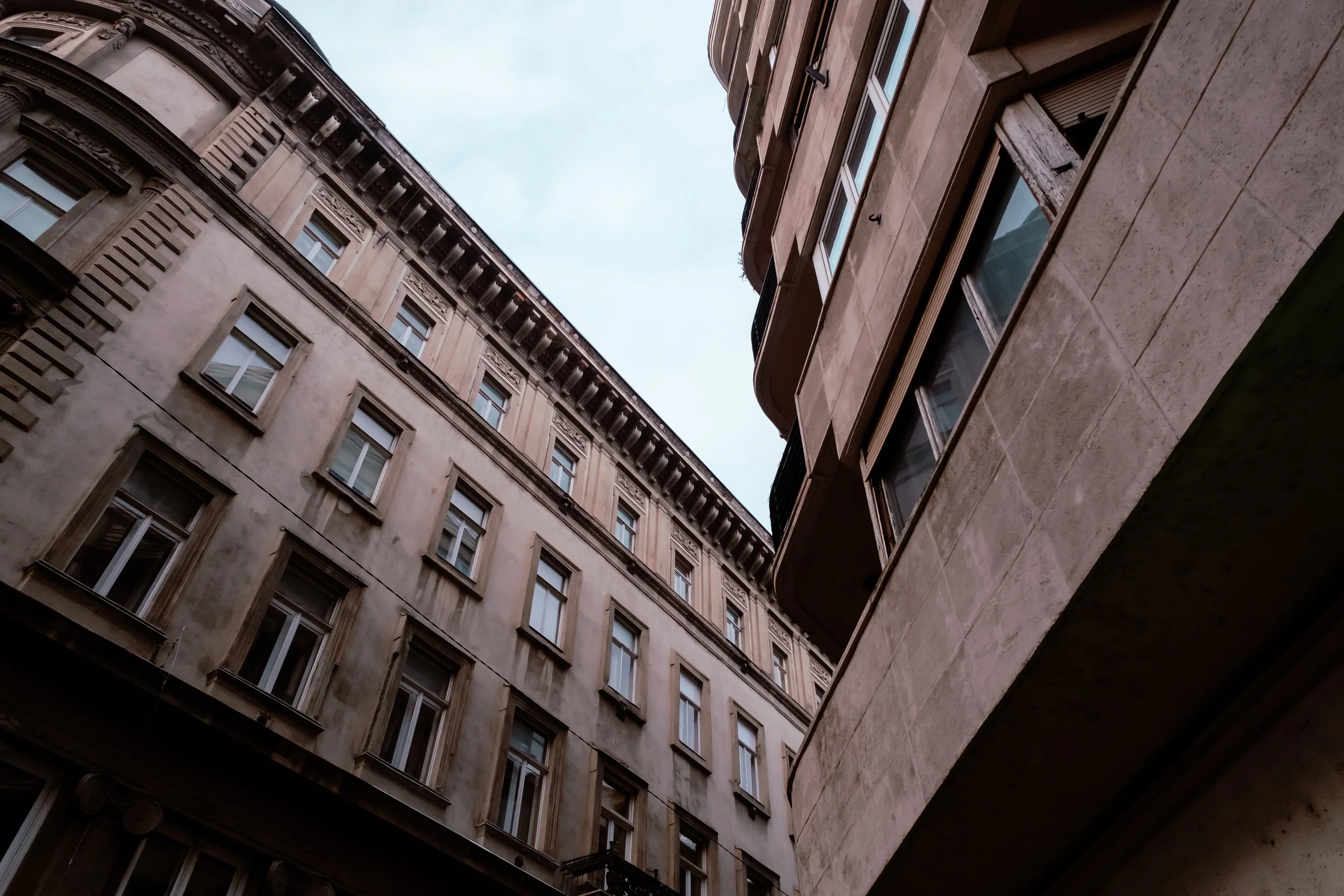 Utsikt uppåt mellan höga byggnader i en stad.