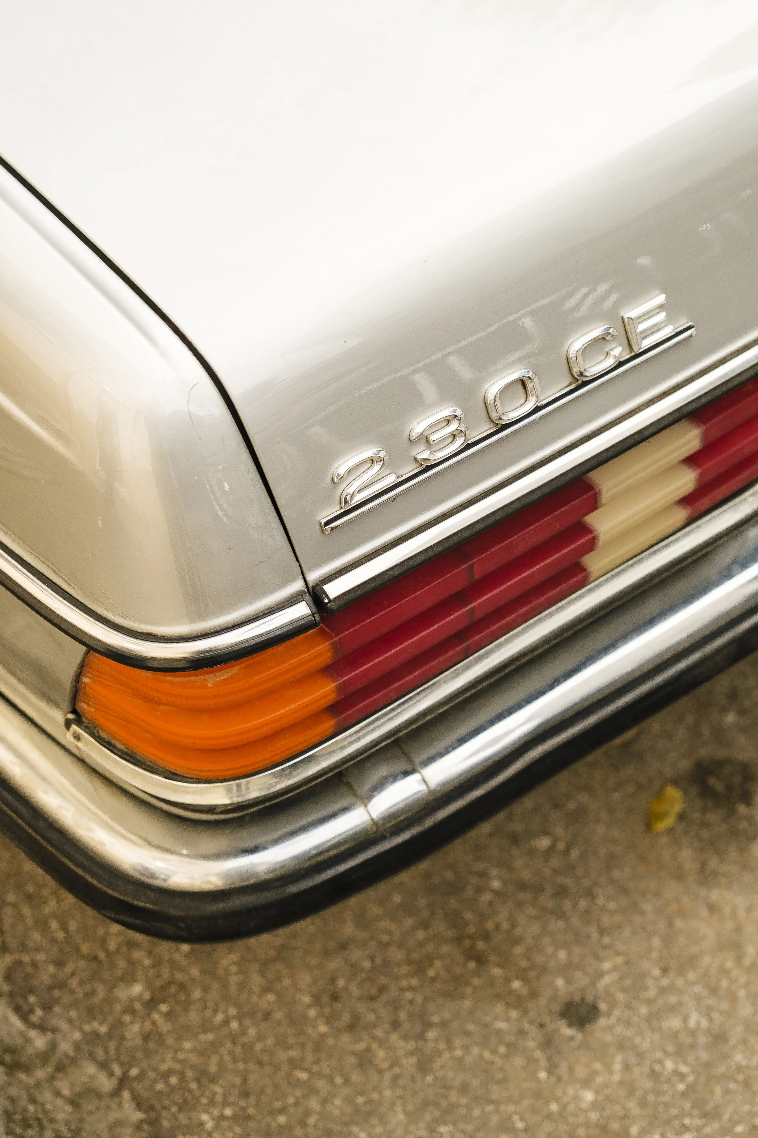 Närbild av bakfoten på en silver BMW 280GE med delvis synlig röda och gula dekaler på bakljuset.