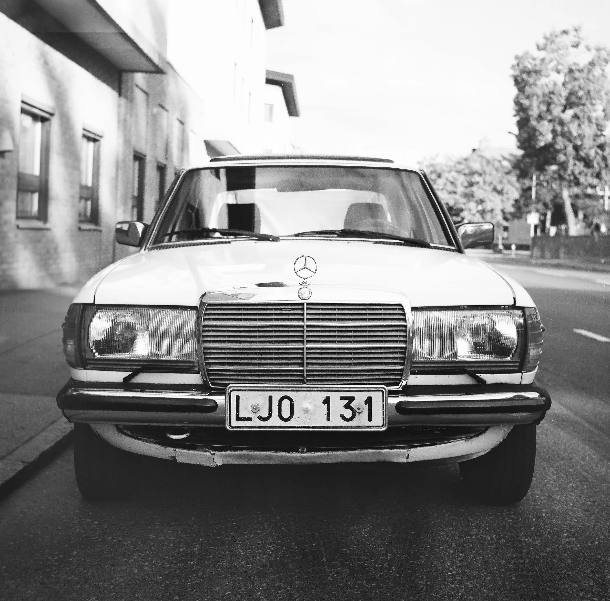 Svartvit bild av en klassisk Mercedes-Benz bil som är parkerad på en gata.