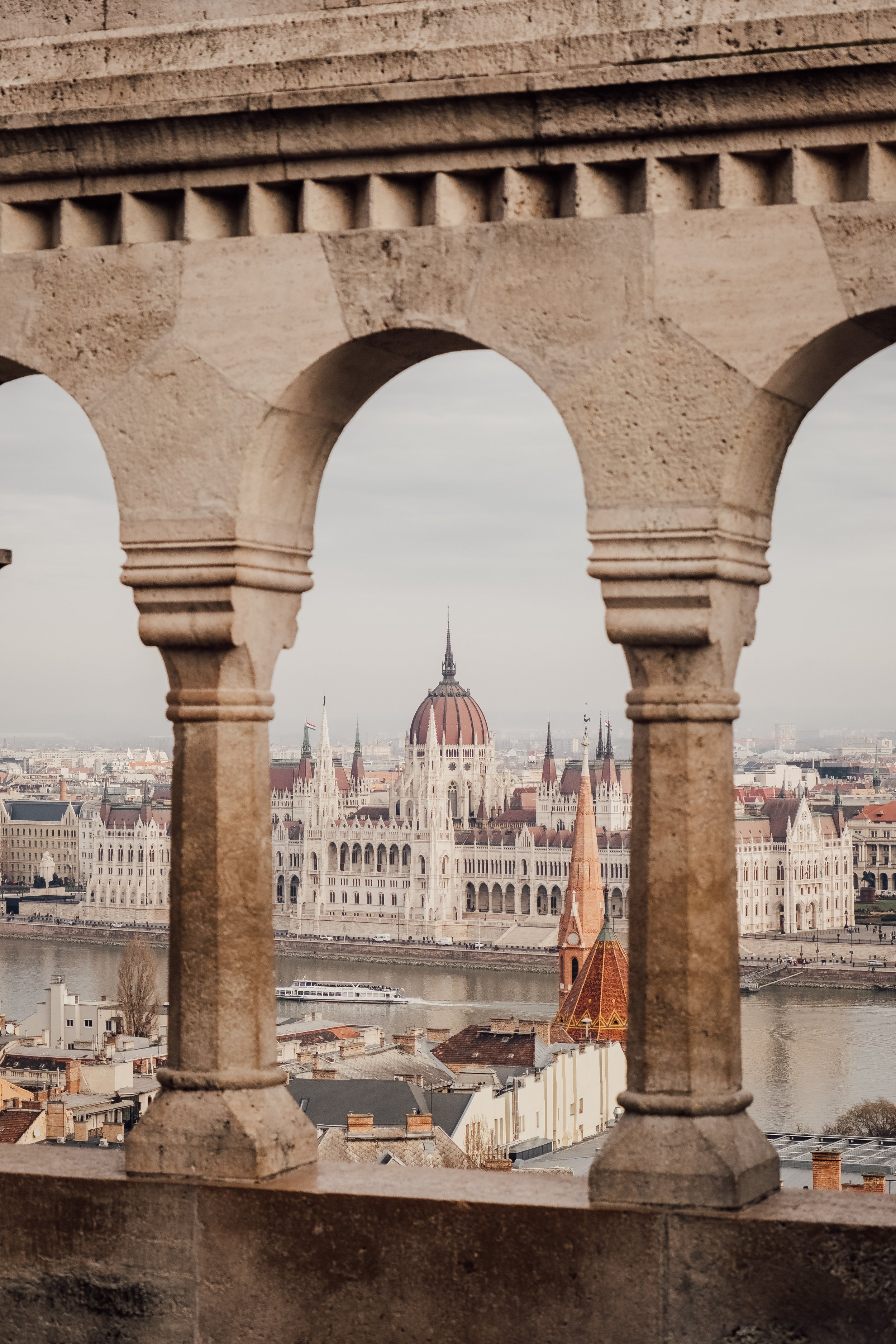 Utsikt över parlamentet i Budapest genom en stenarkad.