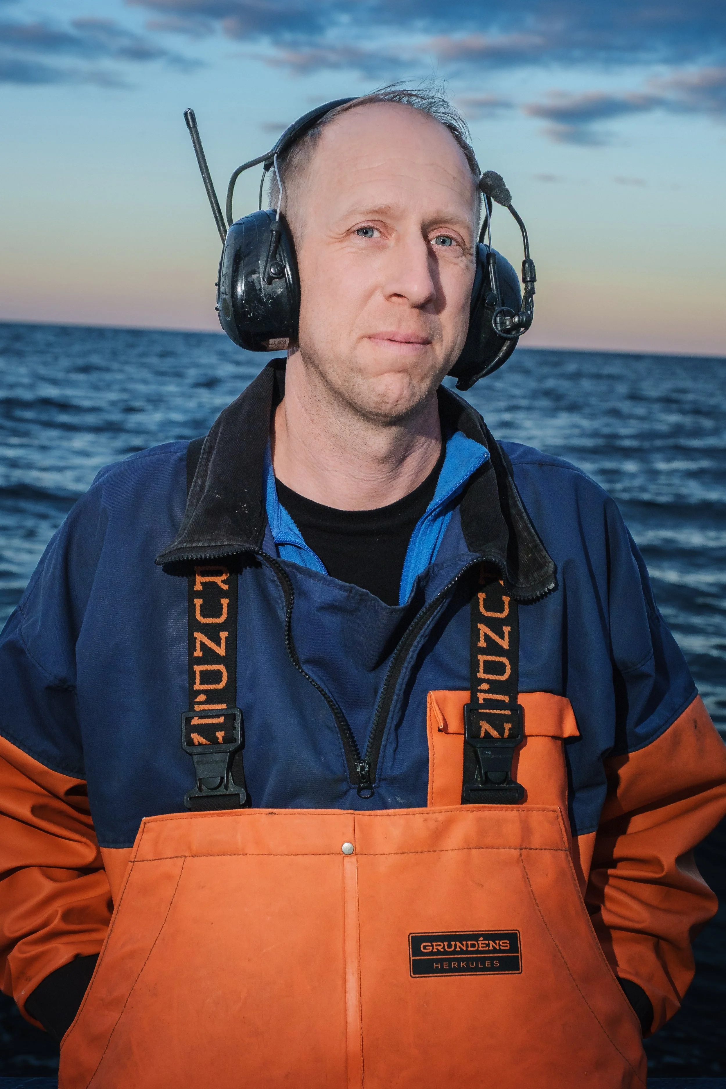 Man i räddningsutrustning på havet vid solnedgången.