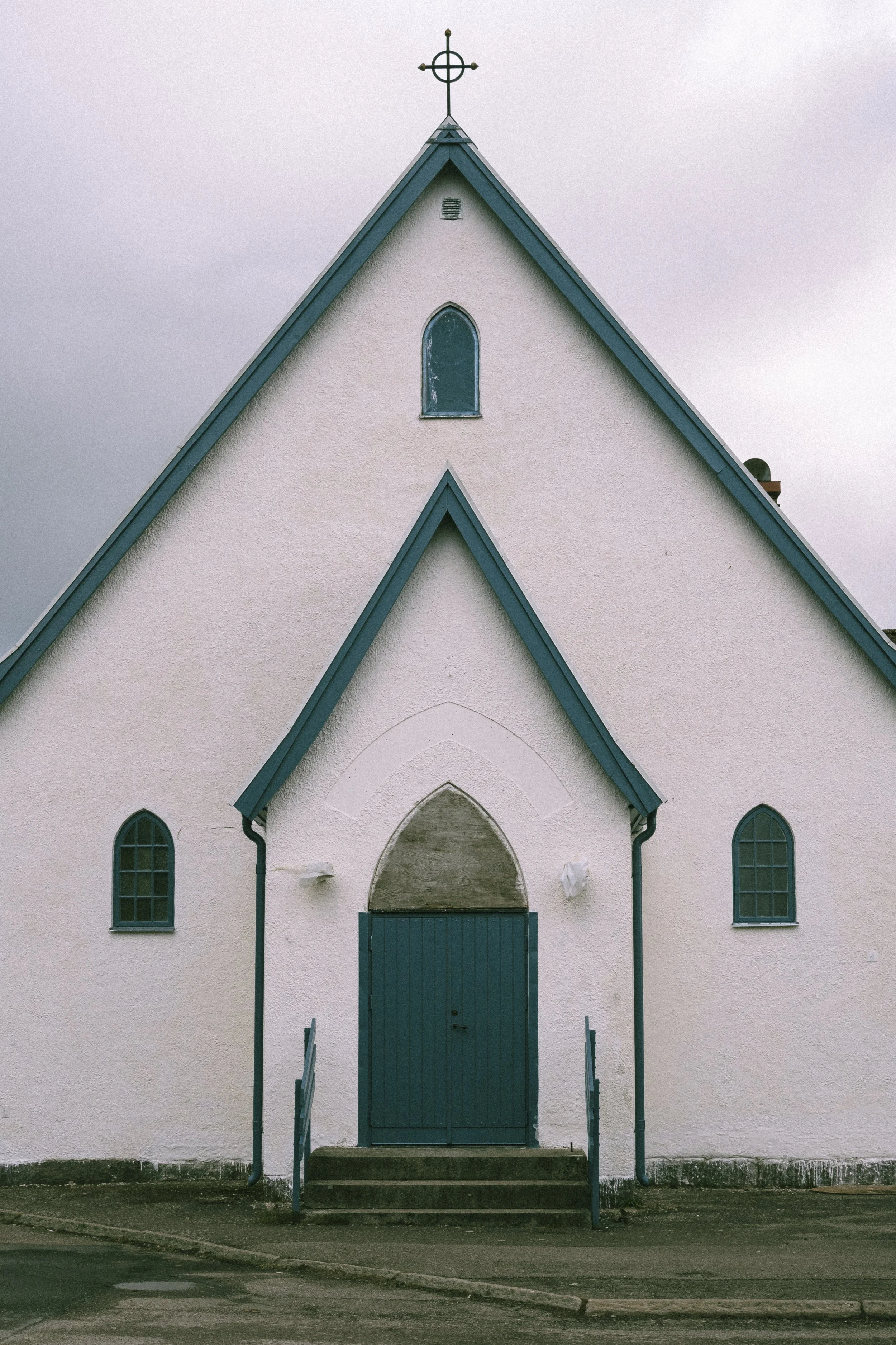 En vit kyrkobyggnad med blå dörr och fönster, samt en korskrans på takspetsen.