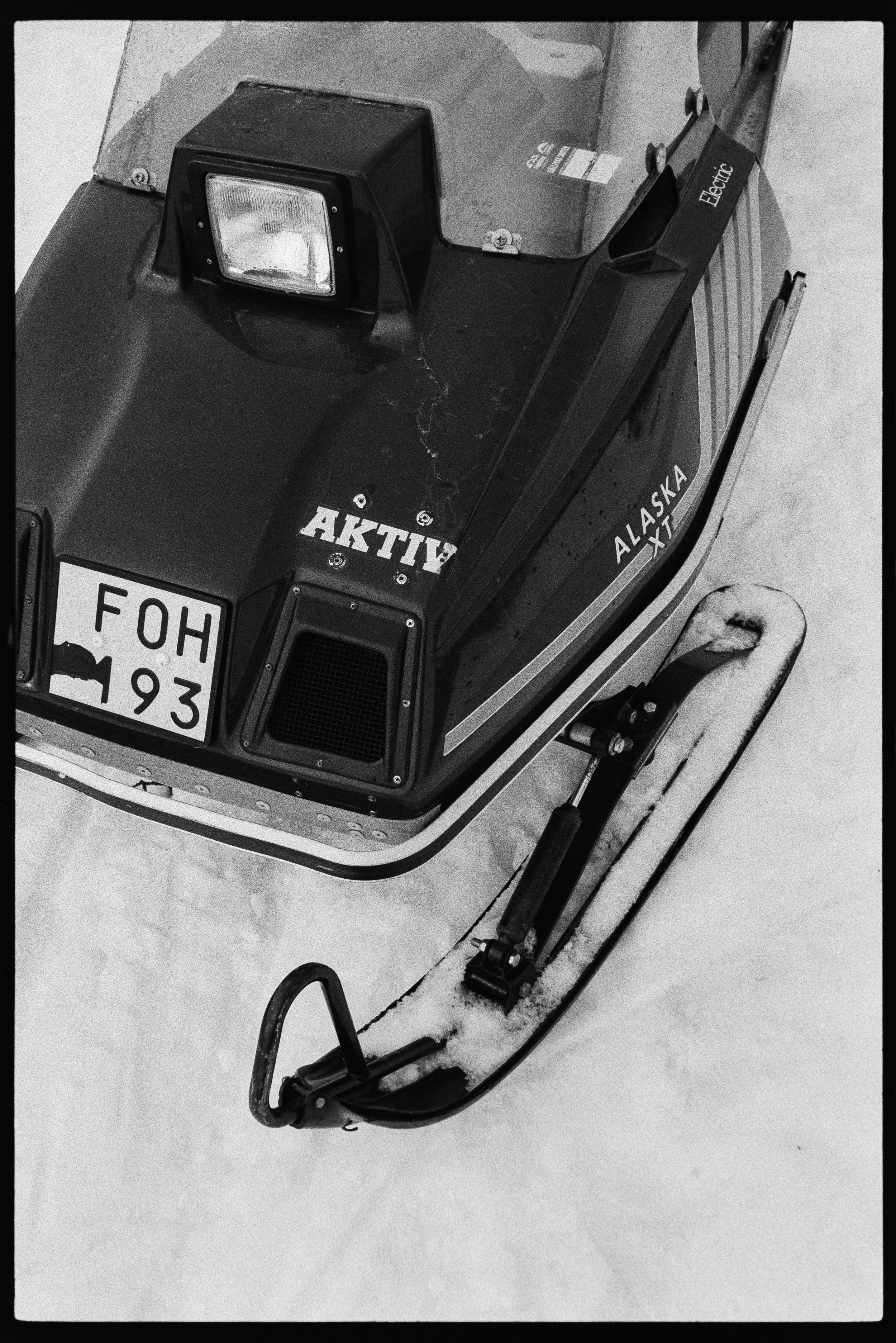 En snöskoter på snö, med texten Alaska XT och Active på den. Snöskotern är svart och har en frontlykta.