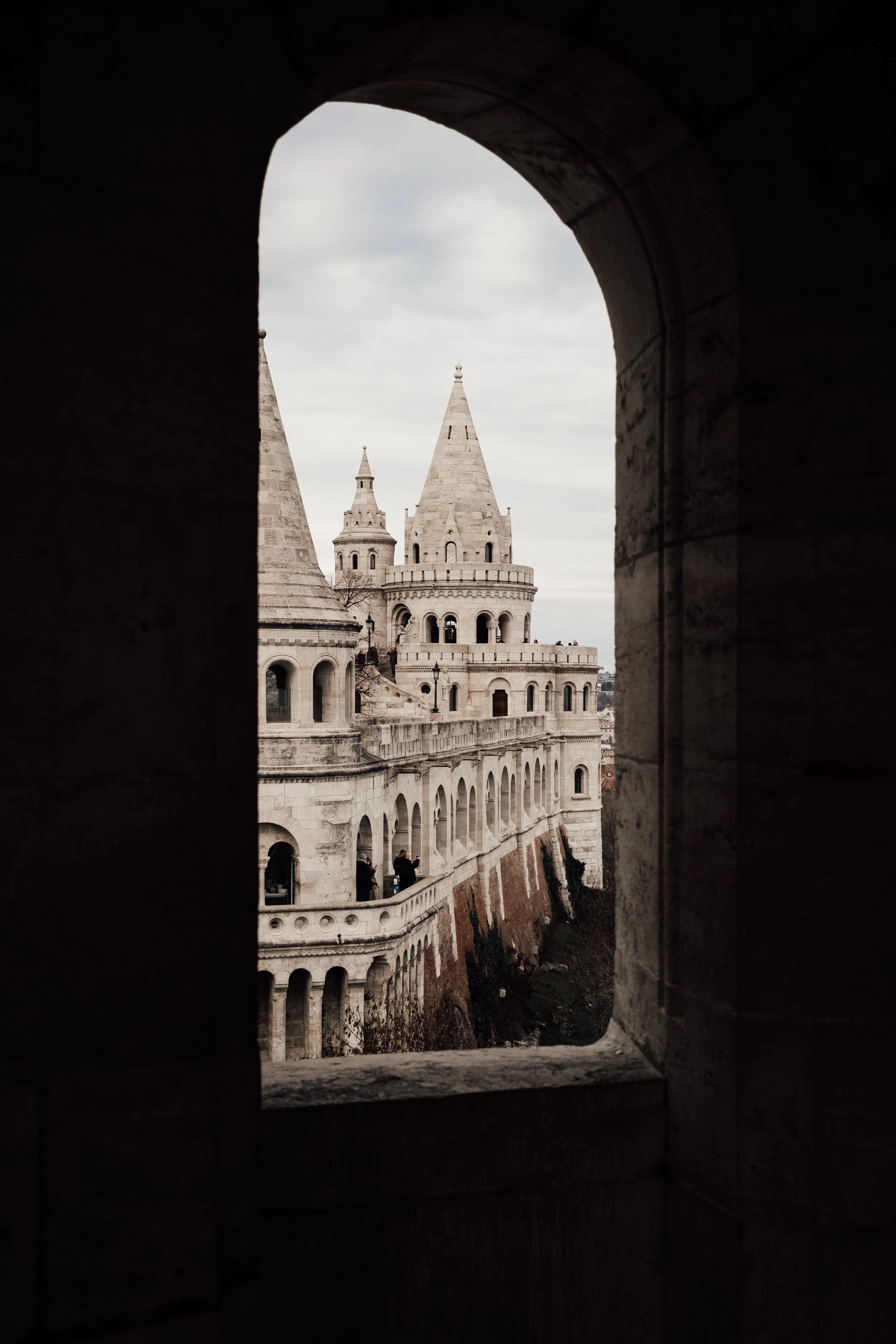 Utsikt av ett slott genom ett fönster i en mörk vägg, med flera torntorn på slottet