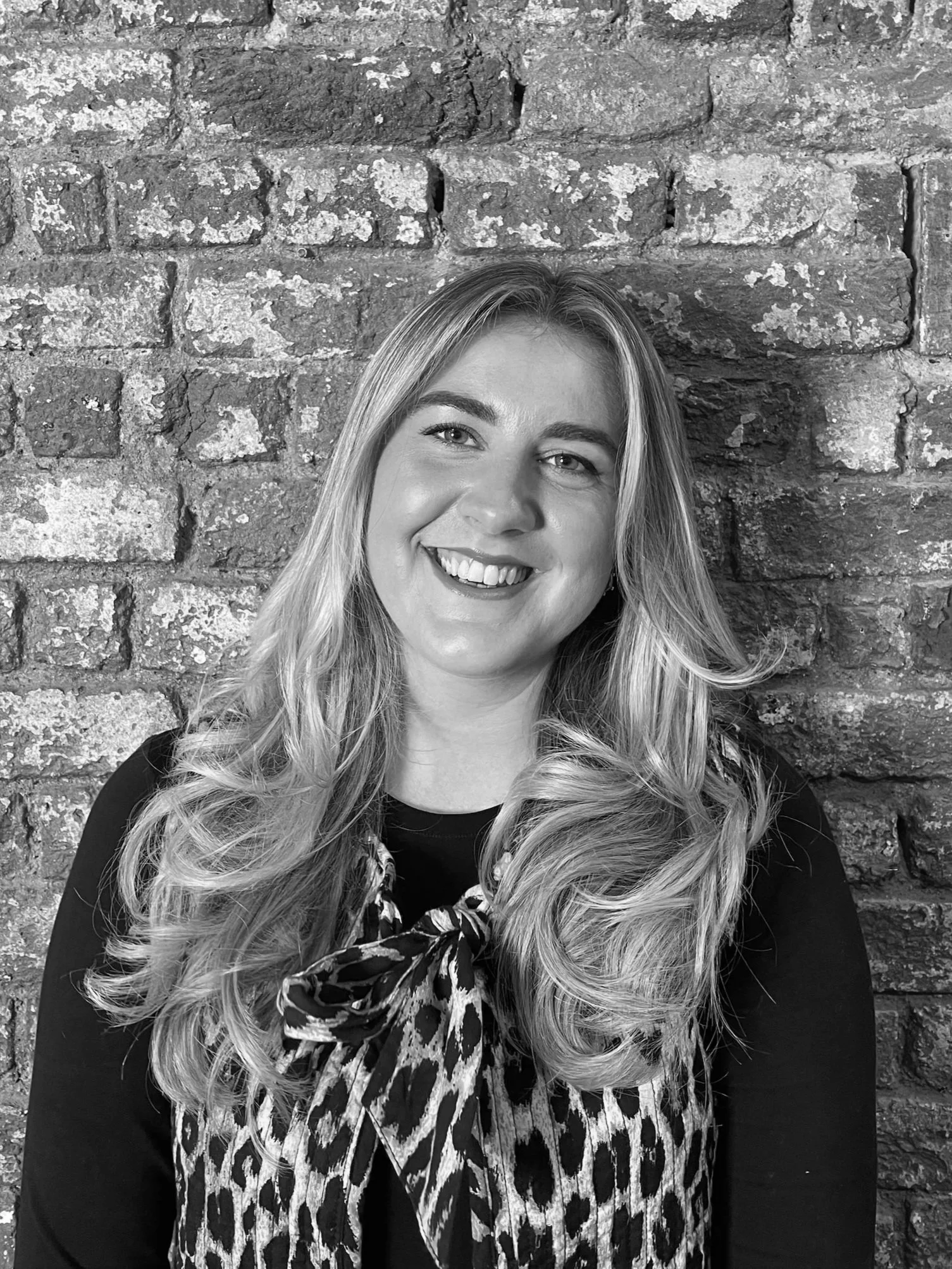 A smiling woman with long hair in a black and white photo.