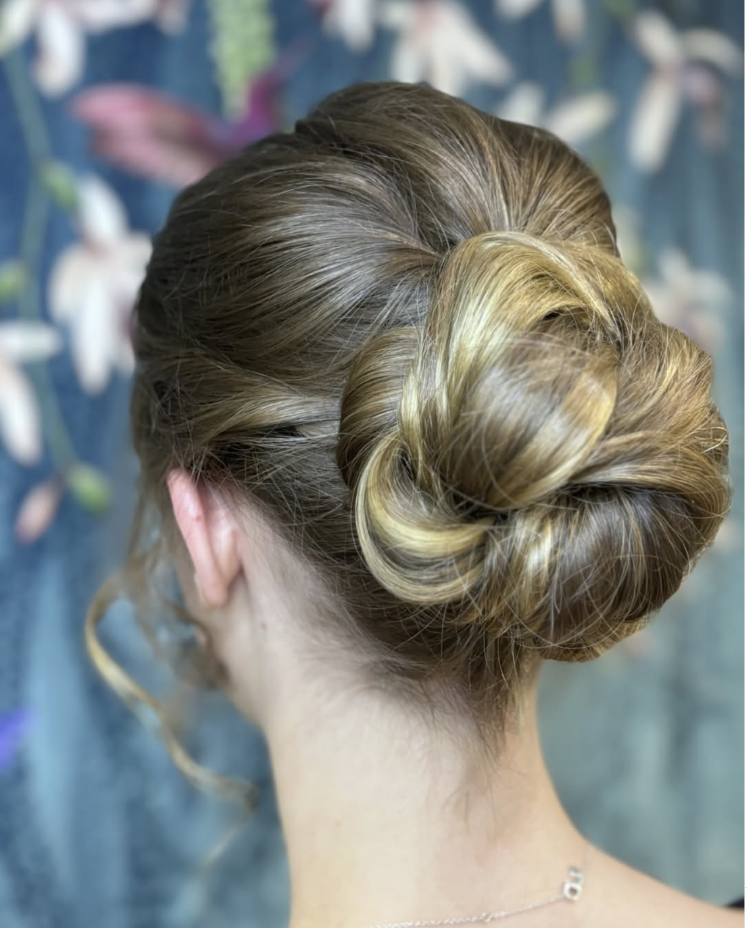 Updo hairstyle with a twisted bun in blonde hair on a woman's head, shown from the back.