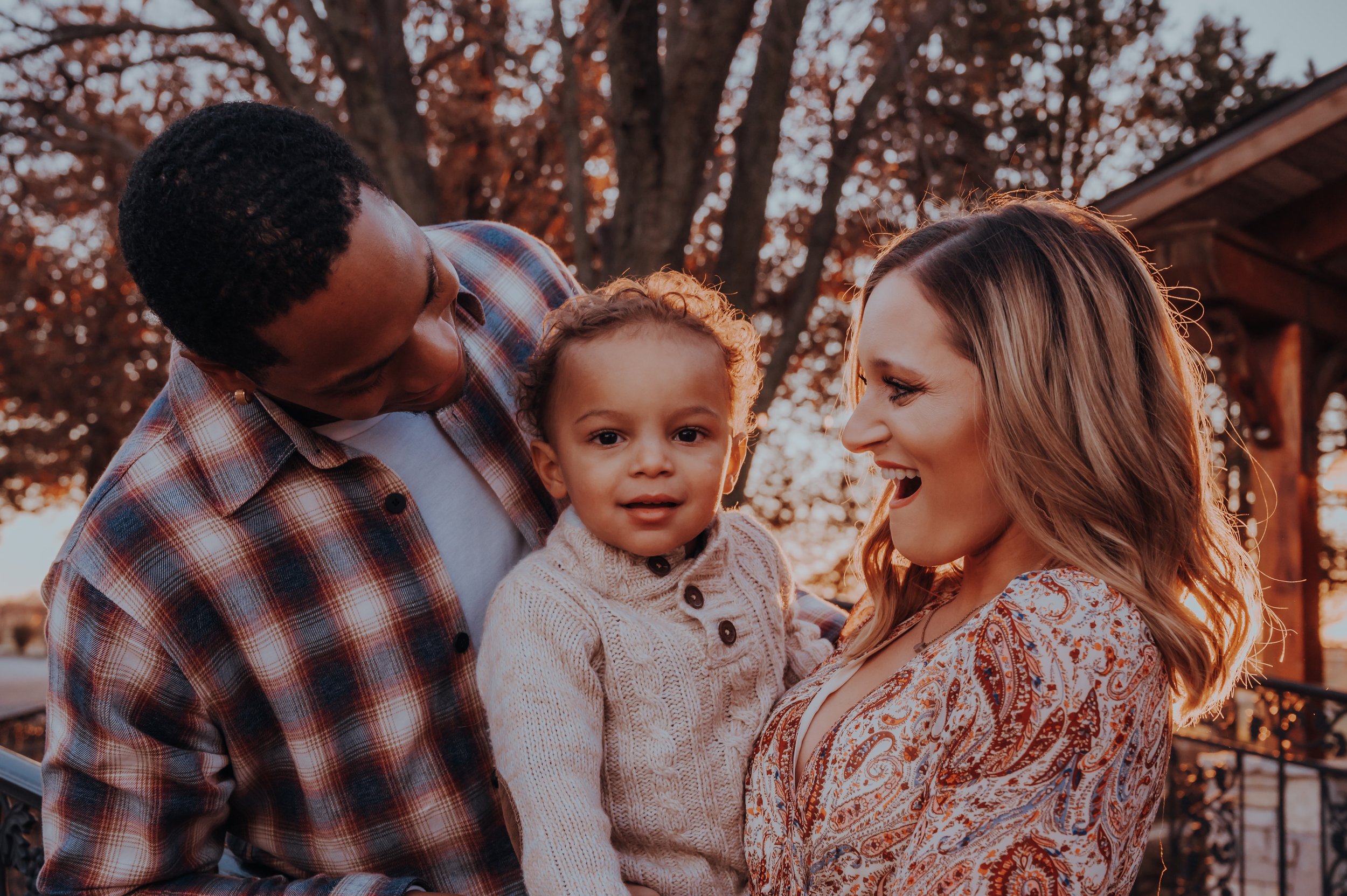Happy family with a child and two adults outdoors during autumn.