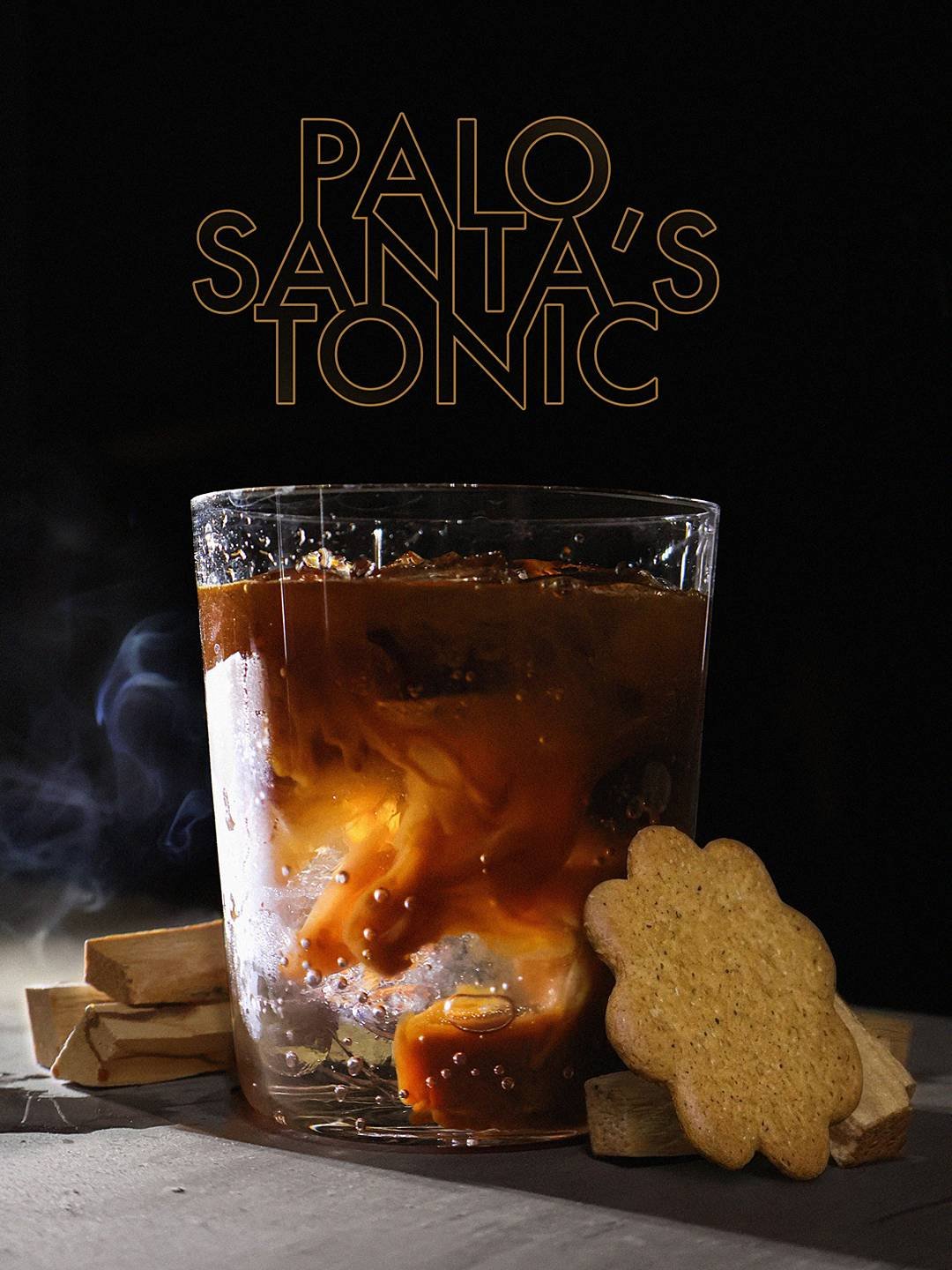 A glass of iced coffee with swirling cream, placed on a wooden surface with a biscuit cookie and wooden sticks, against a dark background with the text 'PALO SANTO'S TÓNIC' in gold lettering.
