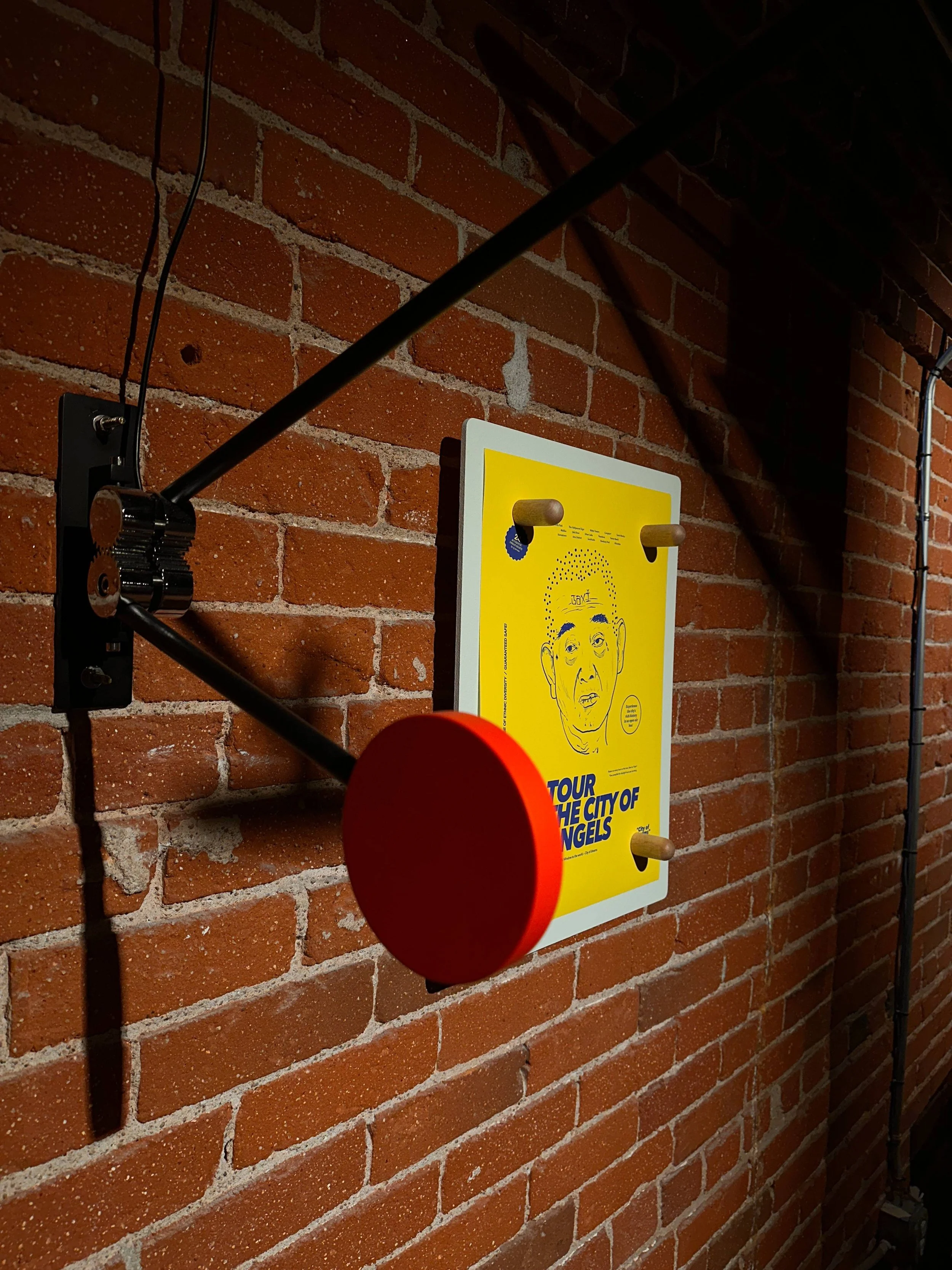 Wall-mounted vintage style art with a yellow poster featuring a line drawing of a person's face and the text "Tour the City of Angels".
