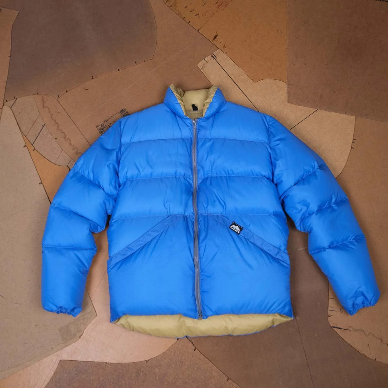 Blue Kluane down jacket laid over its pattern pieces